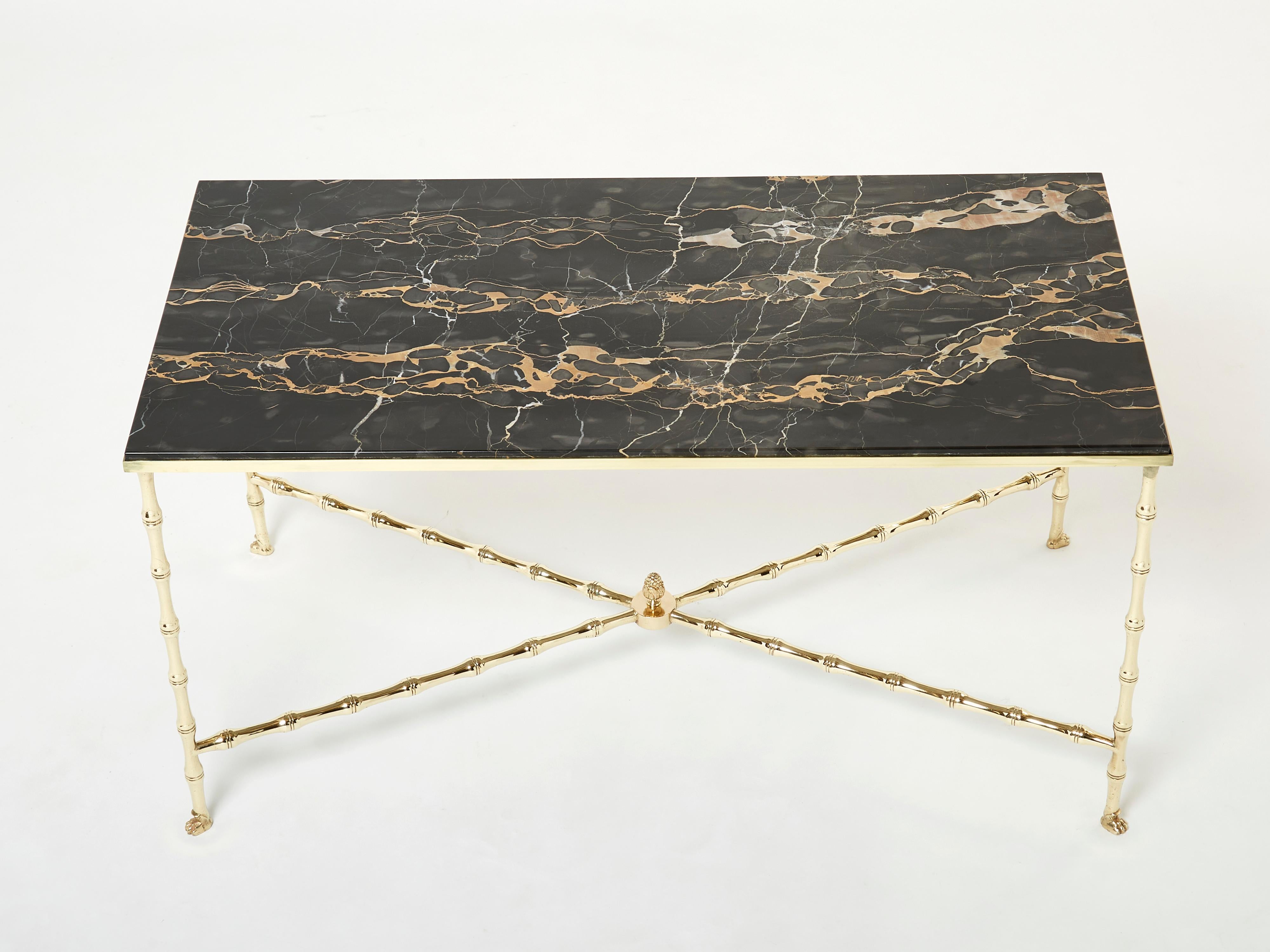 This beautiful coffee table by French house Maison Baguès was created with solid bamboo shaped brass and a beautiful black Portor marble top in the early 1960s. The black top is timeless and smooth, while the brass bamboo feet details provide an