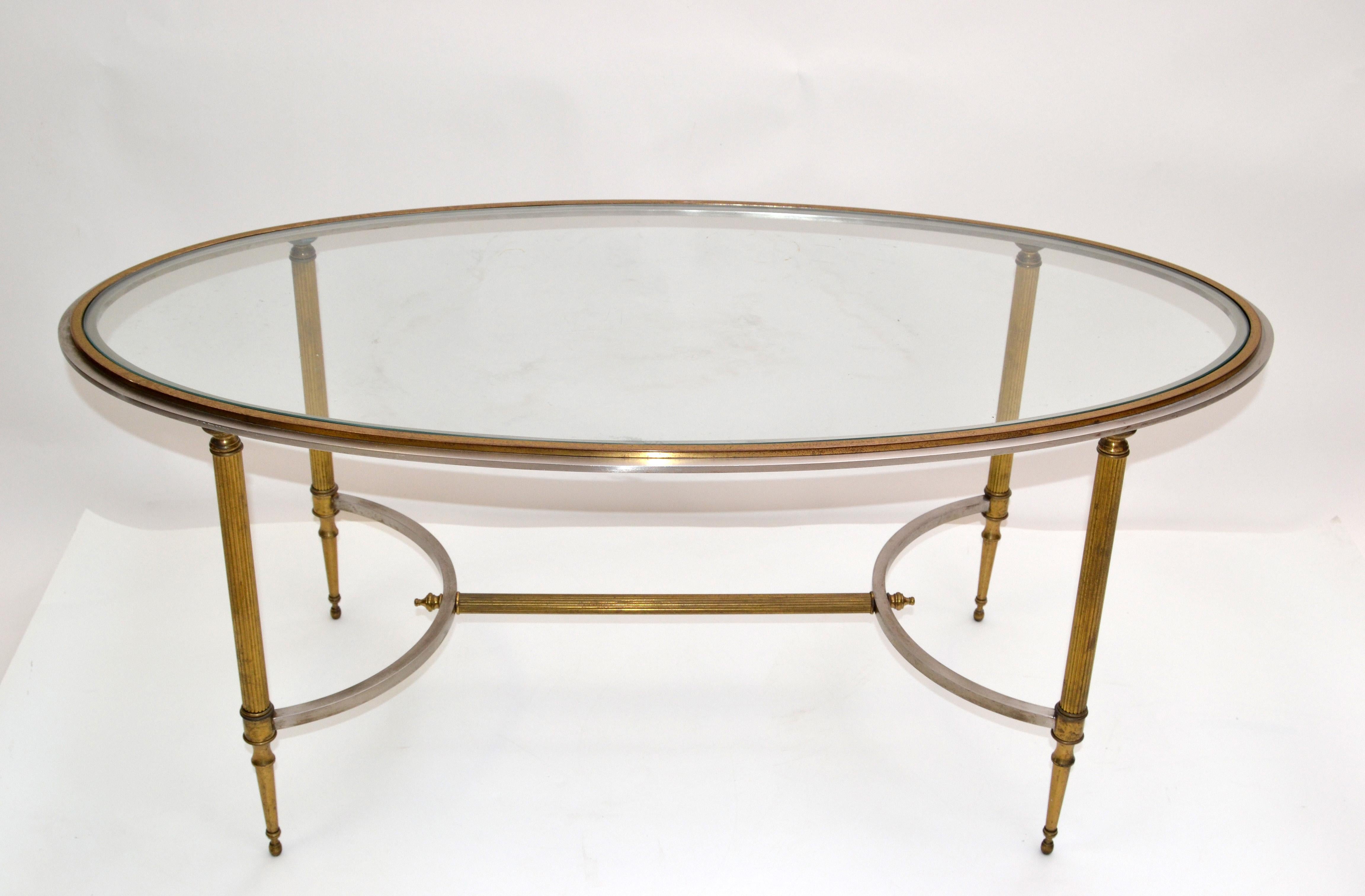 French neoclassical Maison Jansen coffee table in brass with steel borders and oval beveled glass top.
The coffee table is in original condition with warm aged patina to the brass.