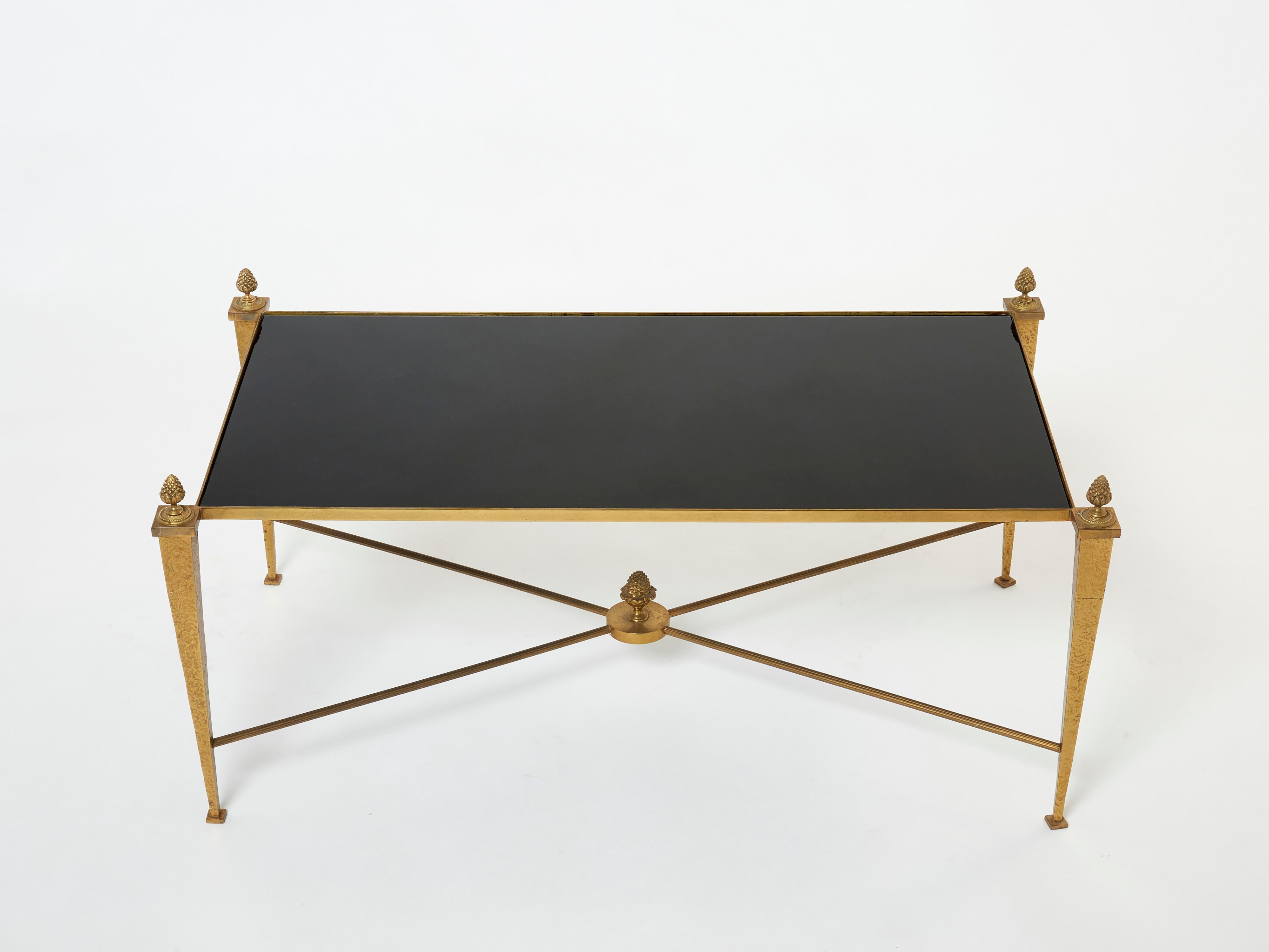 This coffee table by French design house Maison Ramsay was created with high-quality materials, sleek black opaline glass top, gilded wrought iron brass. The black opaline surface is impossibly smooth, while the gilt feet and brass pine cone details