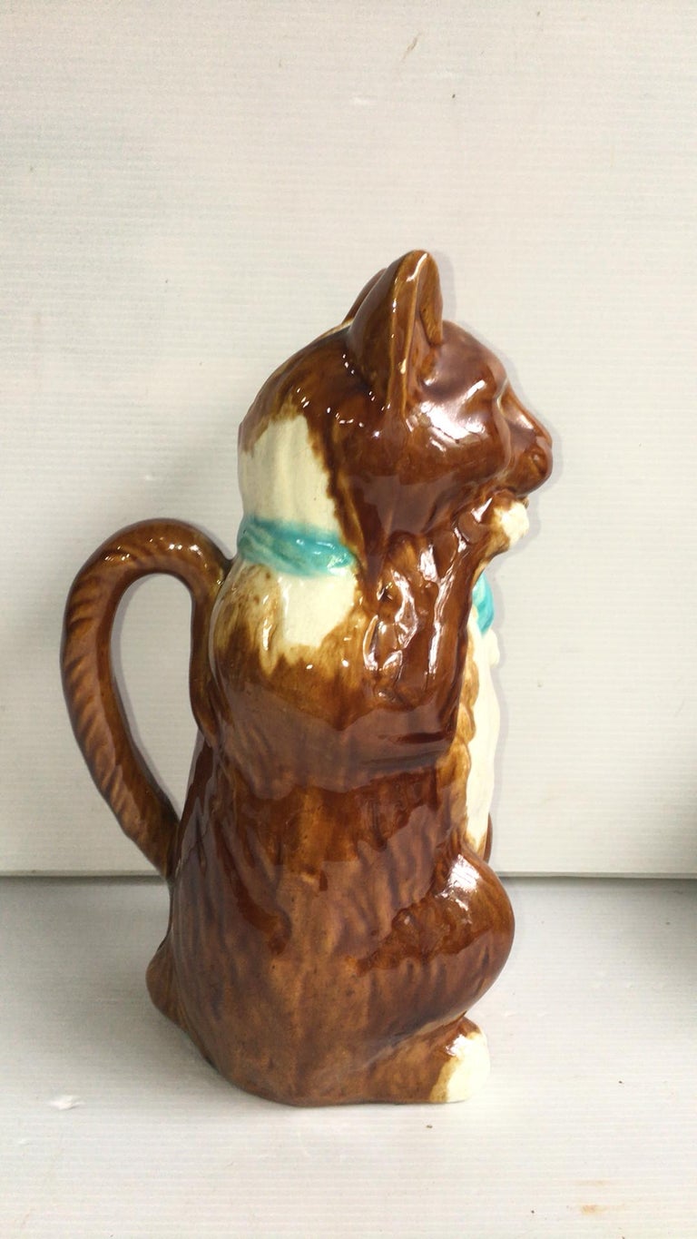 French Majolica cat with mandolin pitcher with blue ribbon, circa 1890.