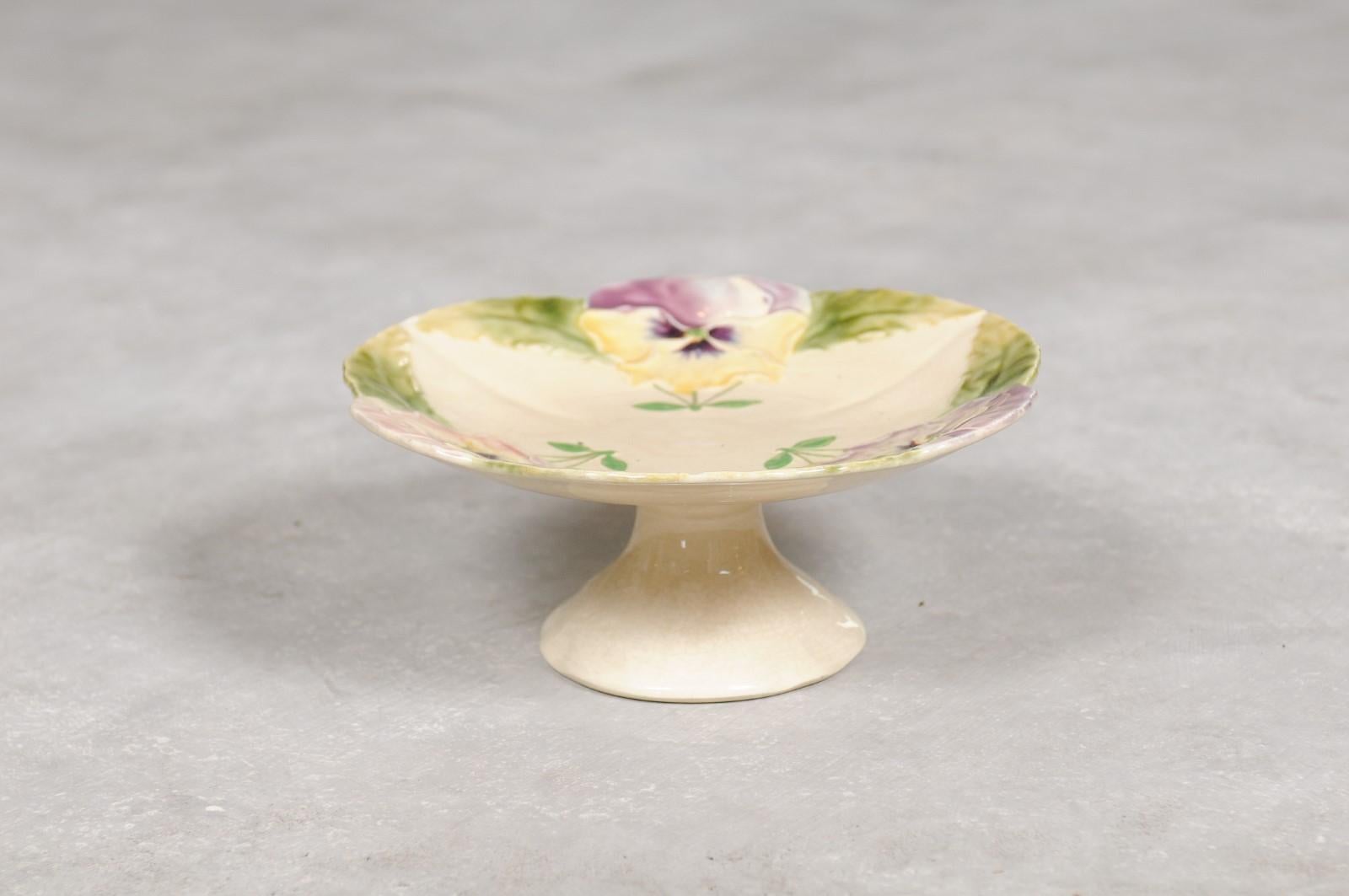 A French majolica compote from the 19th century with pansies and scalloped edge. Born in France during the 19th century, this compote features a décor of delicate purple pansies adorning the compote's scalloped edge. Flanked with their green leaves,