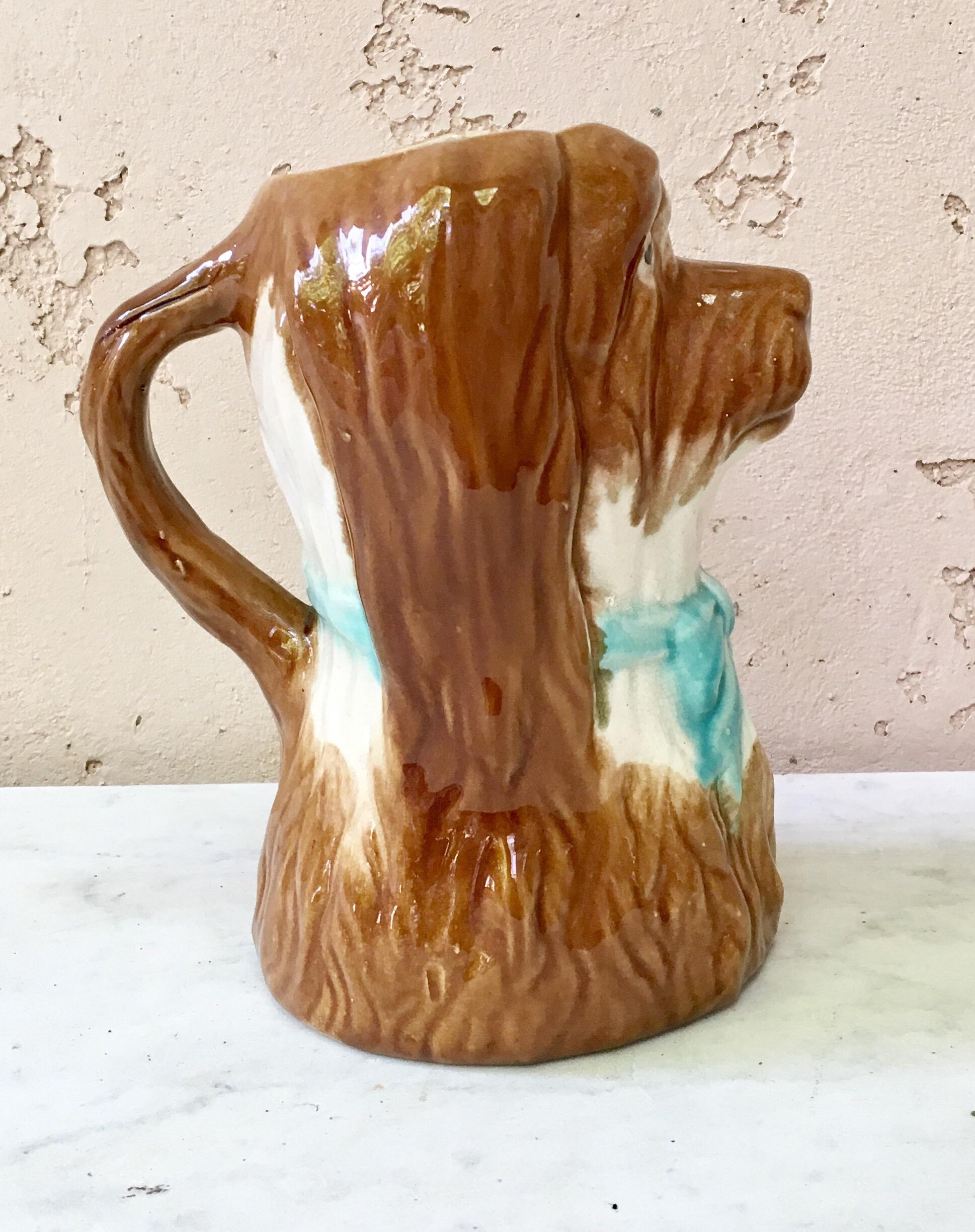 French Majolica dog pitcher, circa 1900.
White and brown dog with a blue bow.