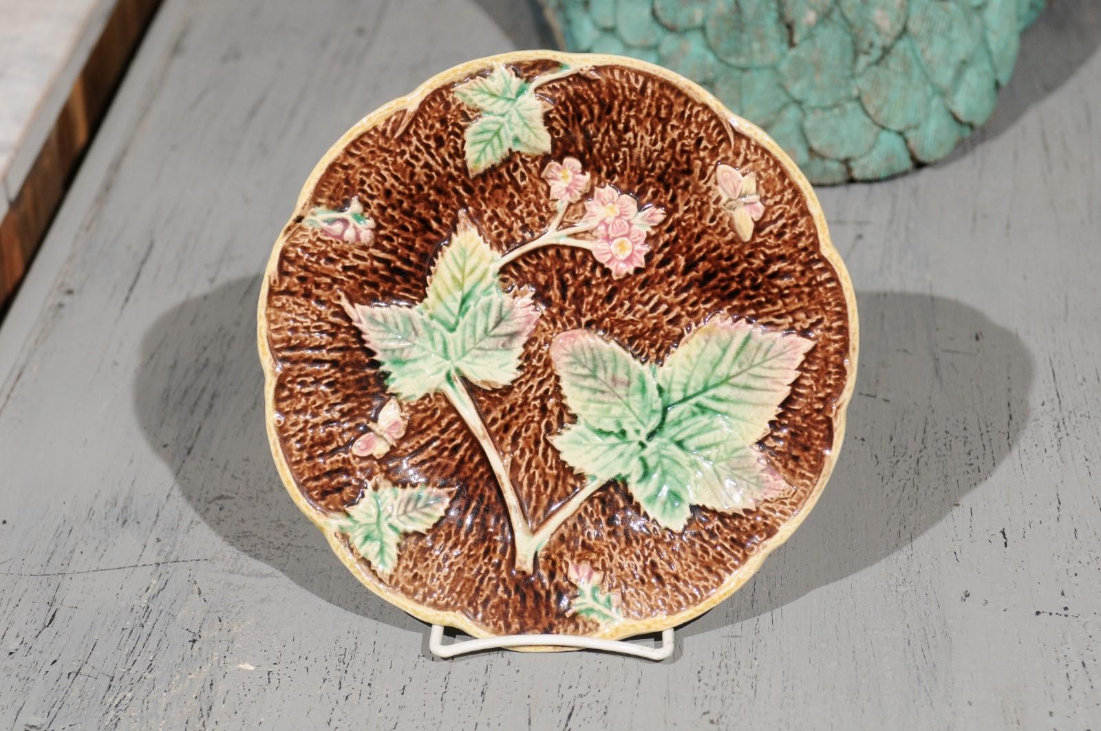 A French Majolica strawberries, flowers and butterfly plate from the mid-19th century. Born in France during the third quarter of the 19th century, this lovely Majolica plate features a delicate décor of green leaves, pink flowers, wild strawberries