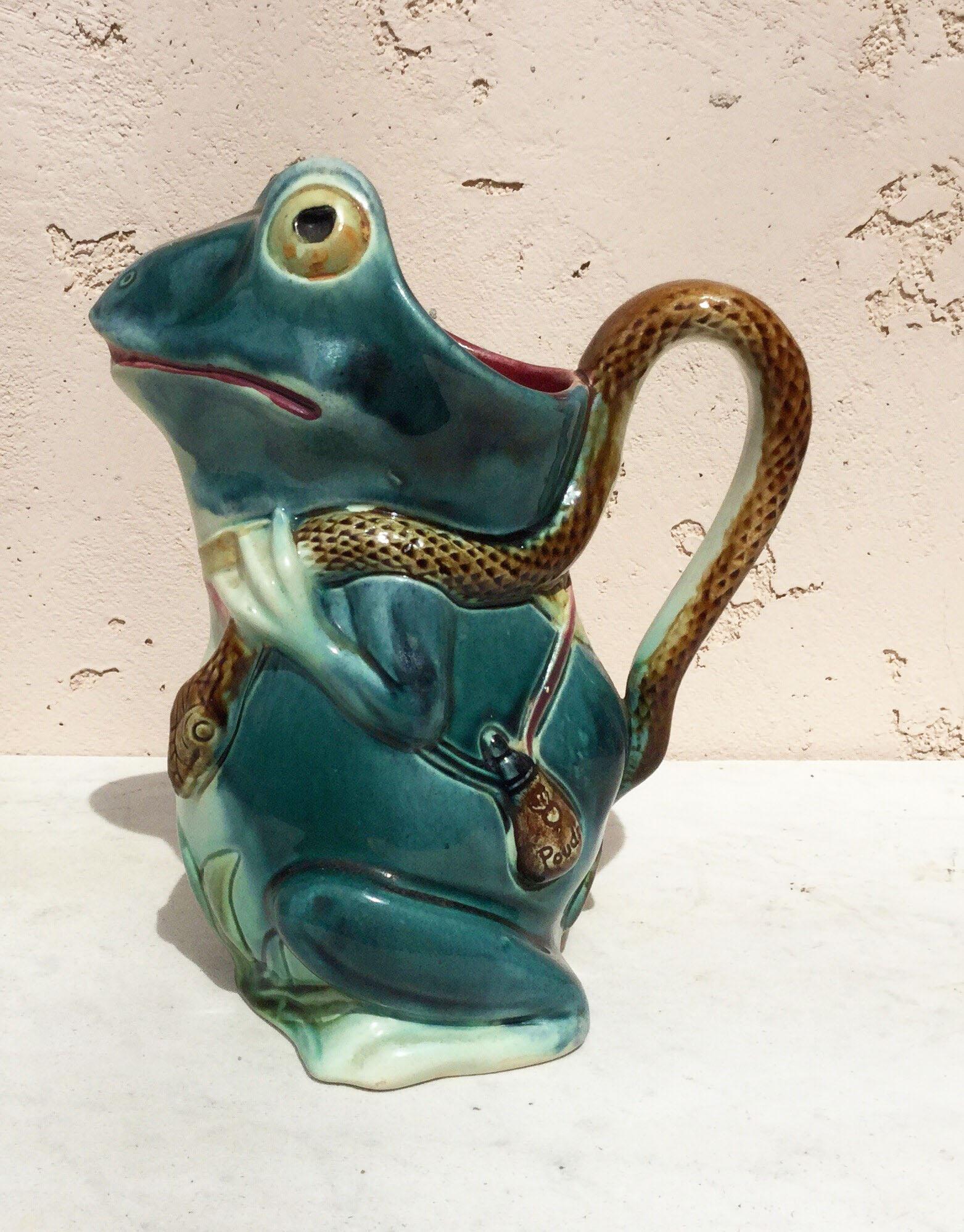 Unusual majolica frog pitcher with a gun and bags, the handle is a snake, circa 1890, marked Orchies.