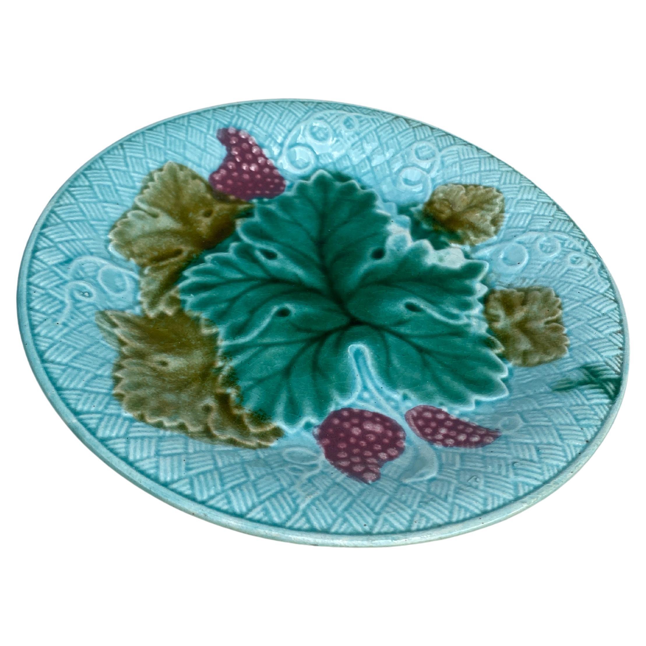 Assiette à raisins Salins en majolique française sur fond bleu clair (Est de la France), vers 1890.