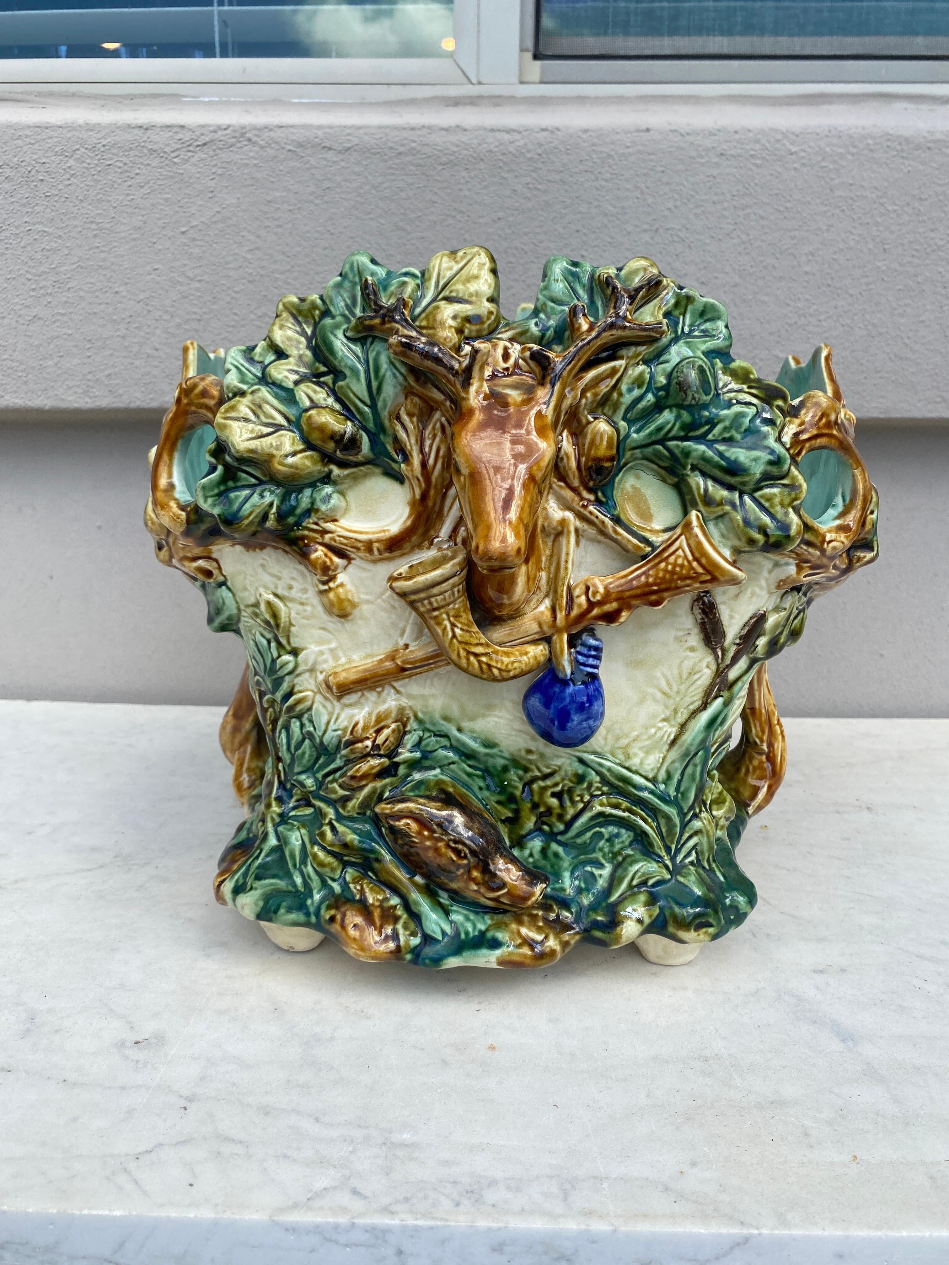 19th Century square Majolica hunt jardinière signed Onnaing.
The planter is decorated with a deer head on the front, oak leaves and acorns, hunting symbols ( gamebag, horn and carbine) on the front also a boar head and a goose.
Measures: 9 3/4 x 11