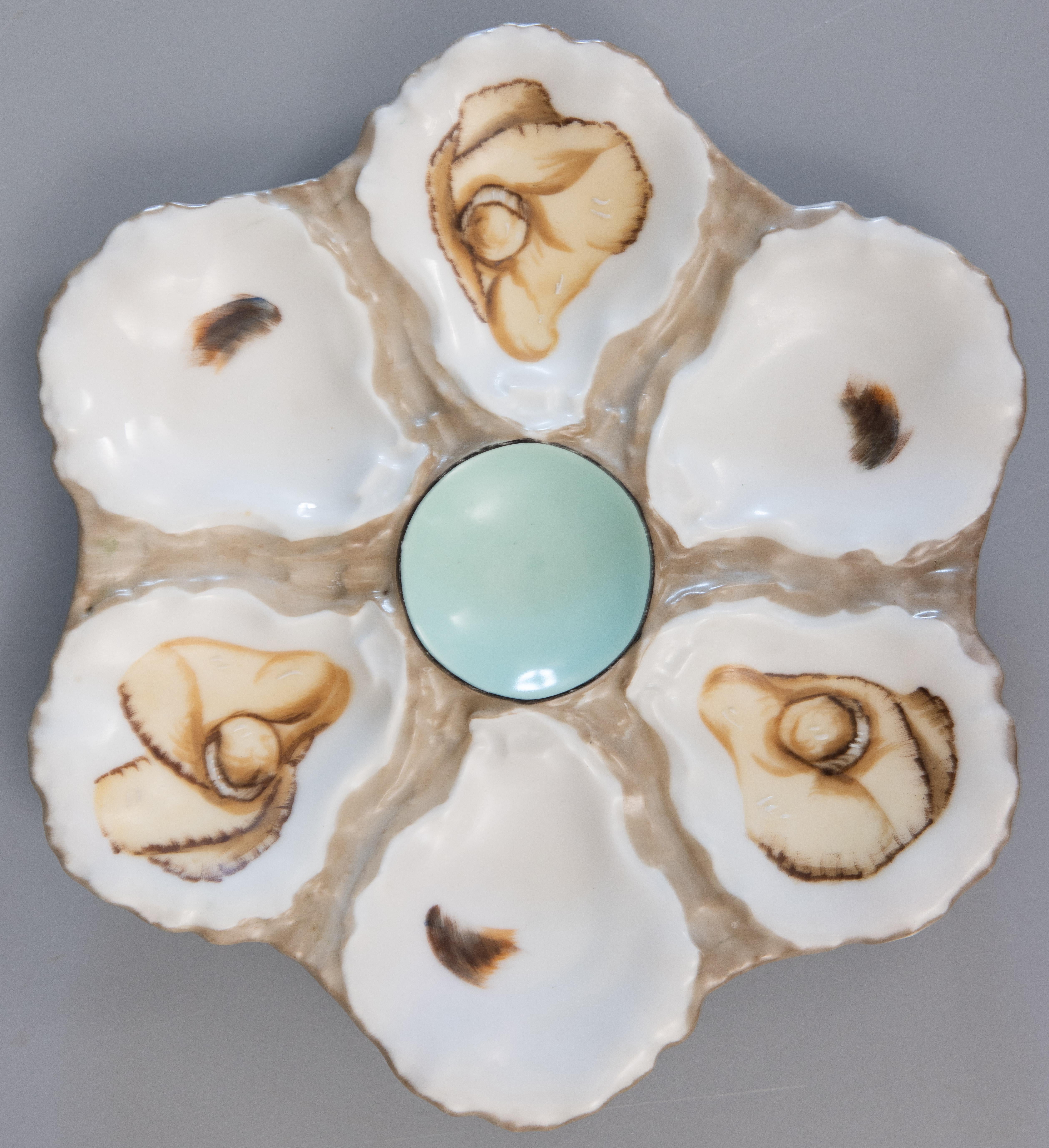 A gorgeous vintage French majolica porcelain oyster plate. This fine quality oyster plate has six wells with hand painted shell decorations and a soft turquoise center. It displays beautifully and would also be perfect for serving.

 