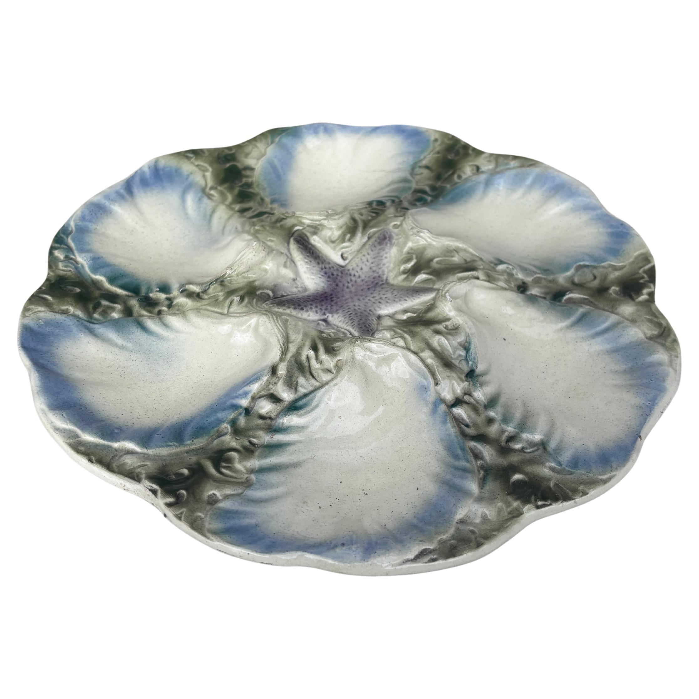 Majolica plate with a starfish with six wells blue and white surrounded by green seaweeds Digoin (East of France), circa 1900.