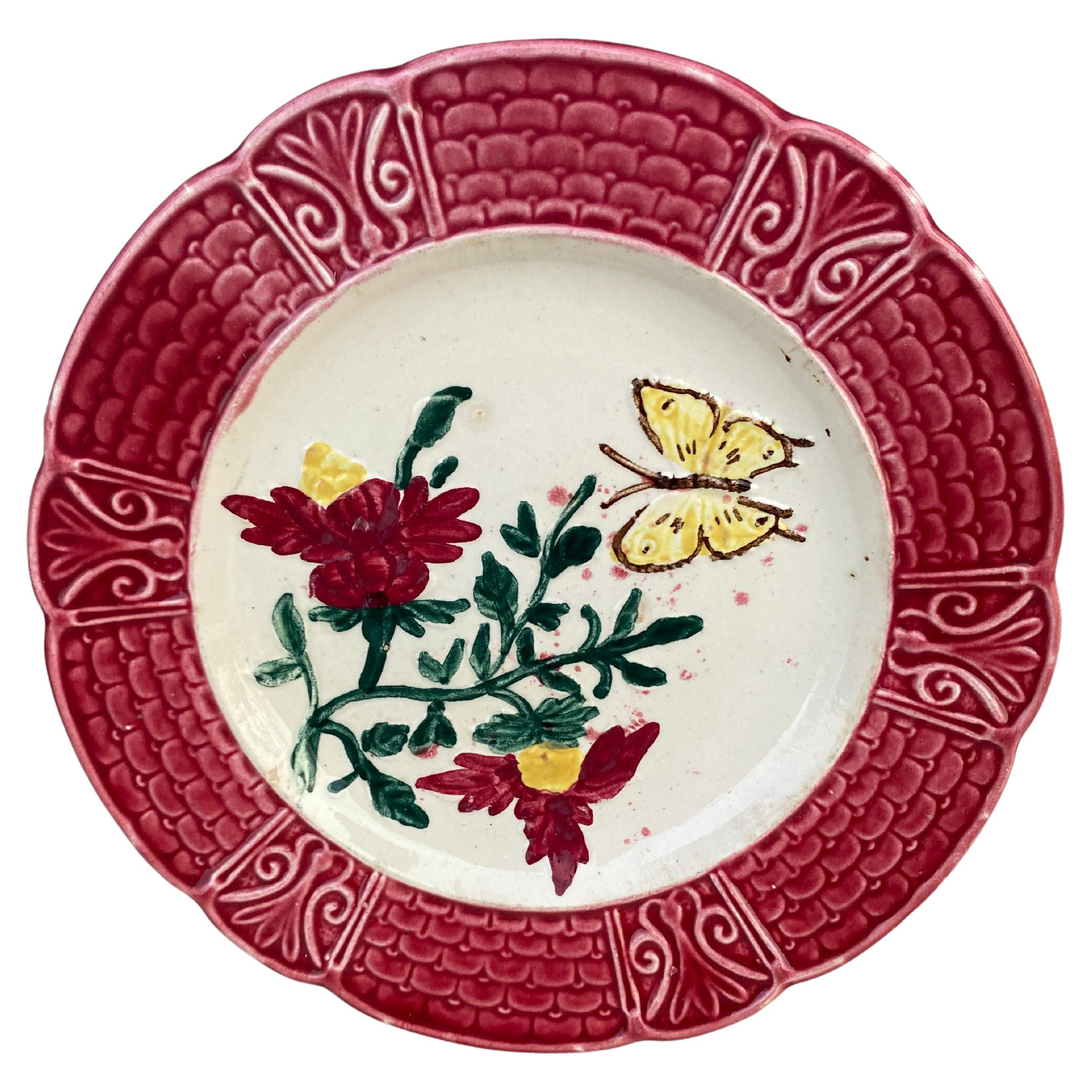 Assiette en majolique française avec fleurs et papillon, datant d'environ 1900