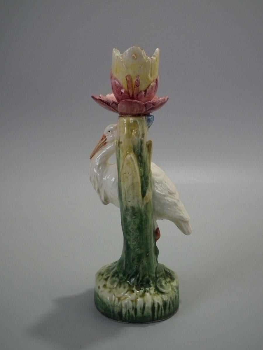 Unidentified French Majolica candlestick holder which features a stork in front of a flower. Coloration: white, cream, green, are predominant. Bears a pattern number, '6352'.