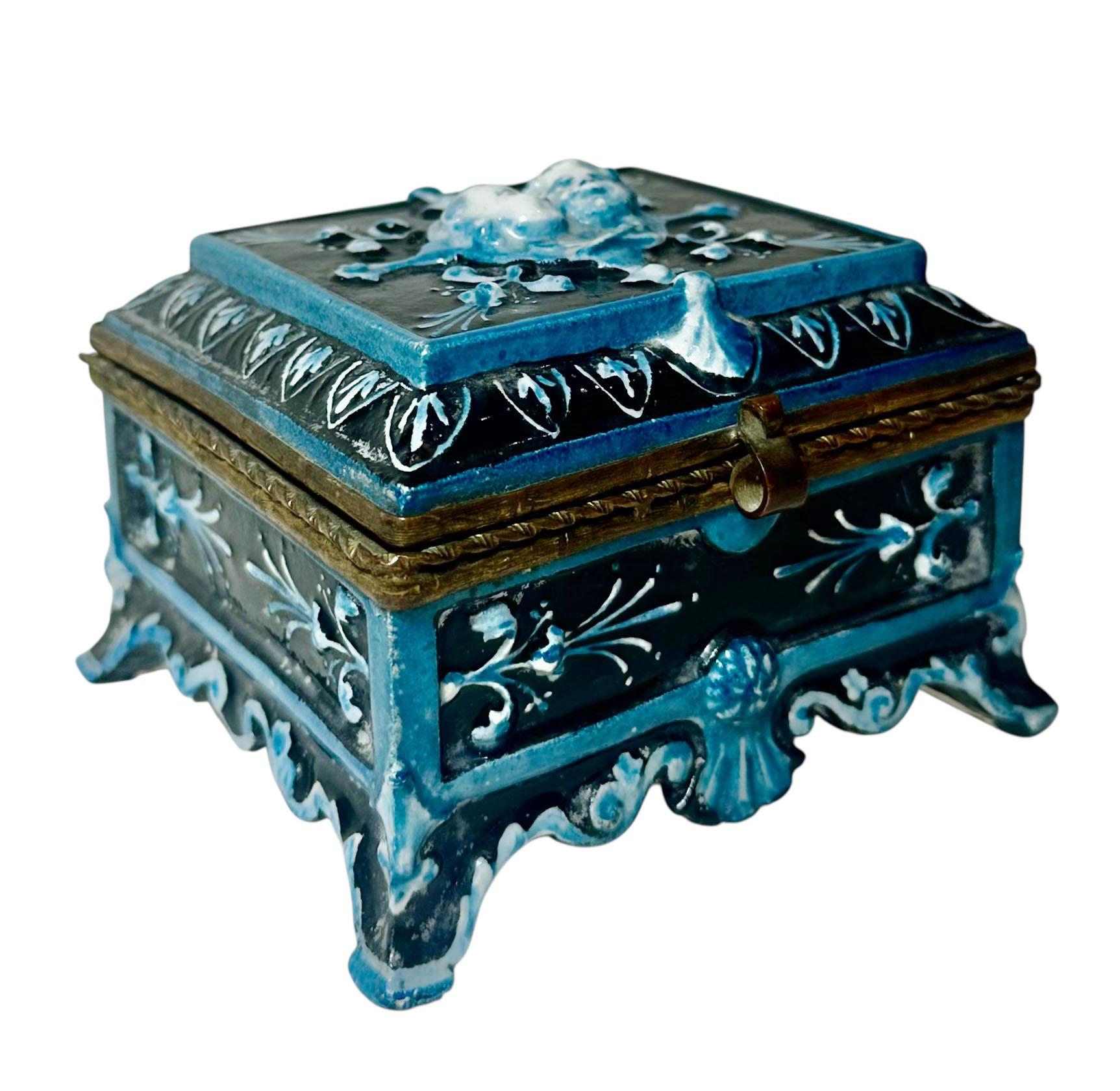 A stunning French majolica trinket box dating to the 1890s, featuring two beautifully modeled cherub heads at the top in an ornate Baroque style.

Glazed in a rich turquoise hue, this piece showcases the depth and brilliance characteristic of fine