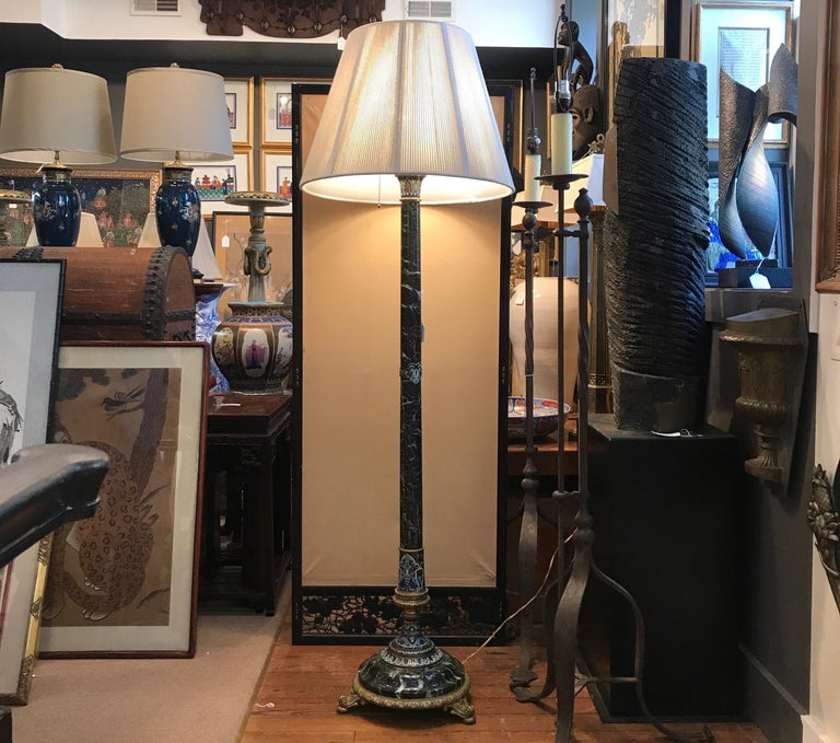 An early 20th Century french marble and gilt bronze floor lamp with Champlevé details.  Two sockets for plenty of light. The shade is for photographic purposes only and not included with the lamp.  68 inches tall, 14 inches diameter at the base.  