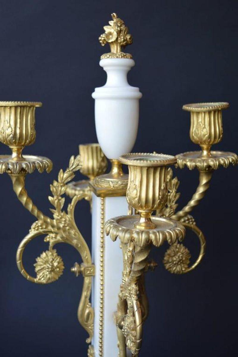 Detailed marble French clock set embellished with gilded bronze.