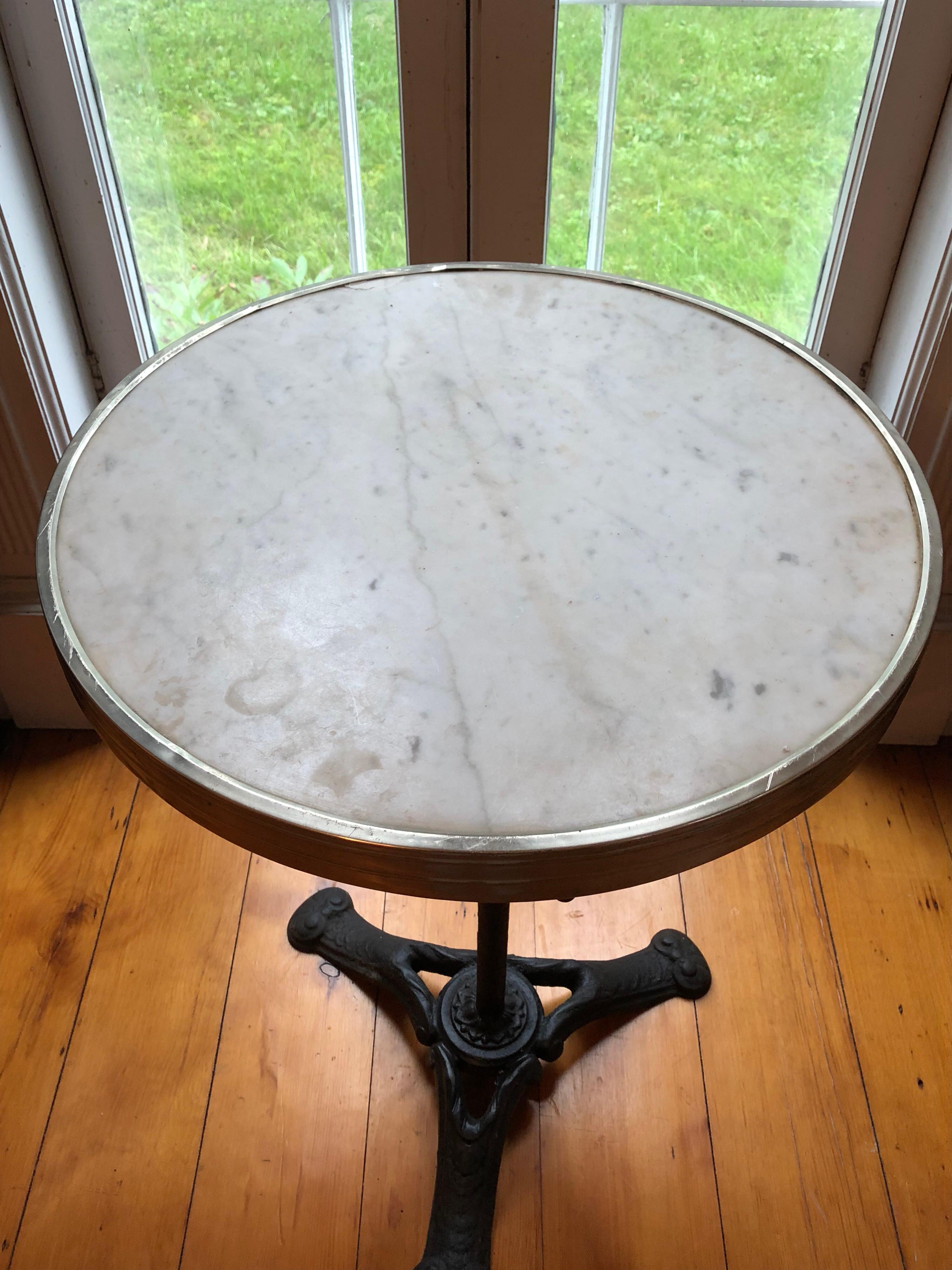 French gilt-metal mounted marble and cast iron cafe or bistro table. One small repair to the marble top very close to the metal rim. Negligible.
