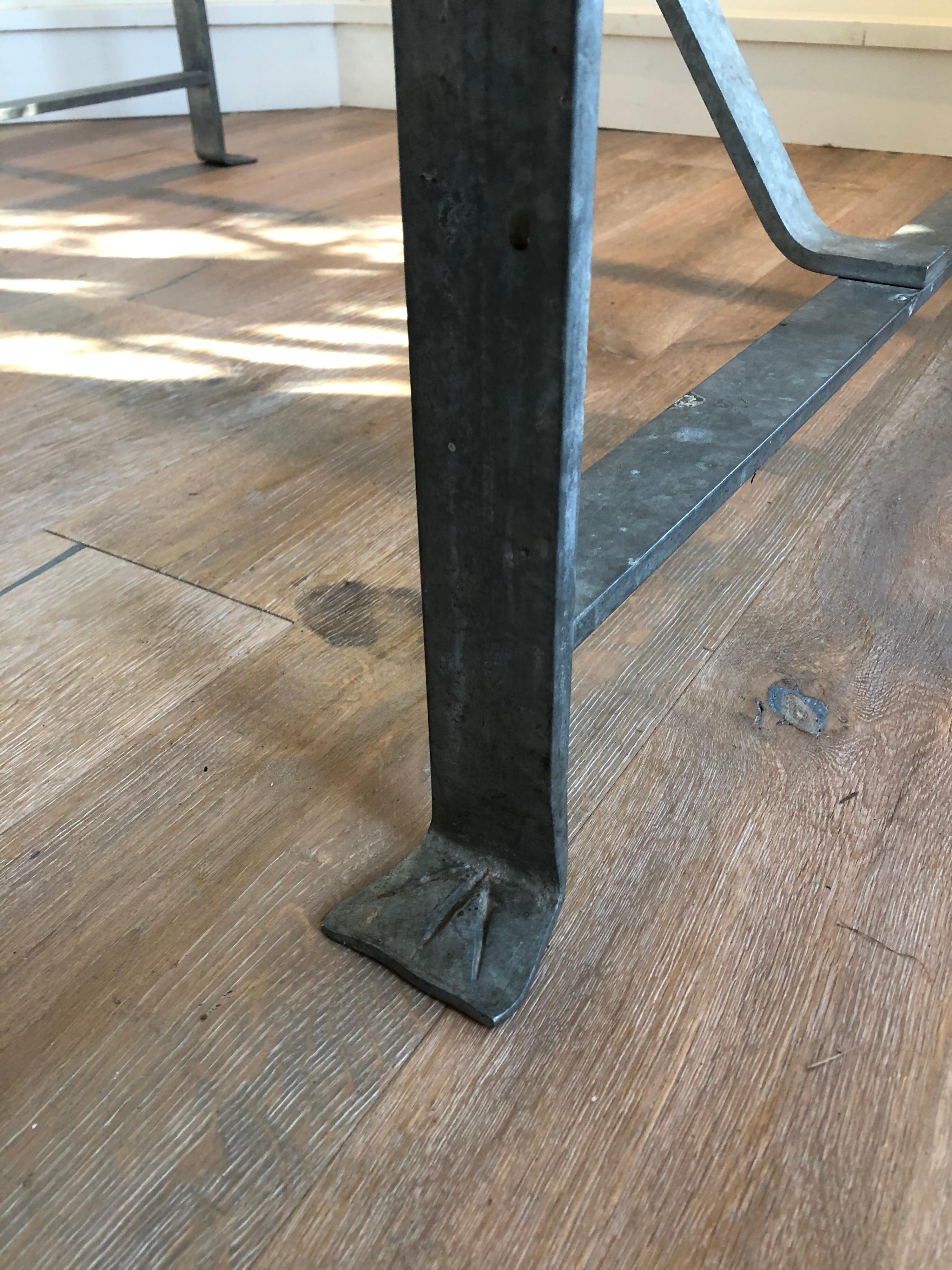 Una mesa de comedor con base de caballete de acero y tapa de mármol Carrera. La base de acero tiene detalles exclusivos, como las patas. Esta pieza de estilo bistró funcionaría bien como mesa de comedor o de escritorio/tarea.
