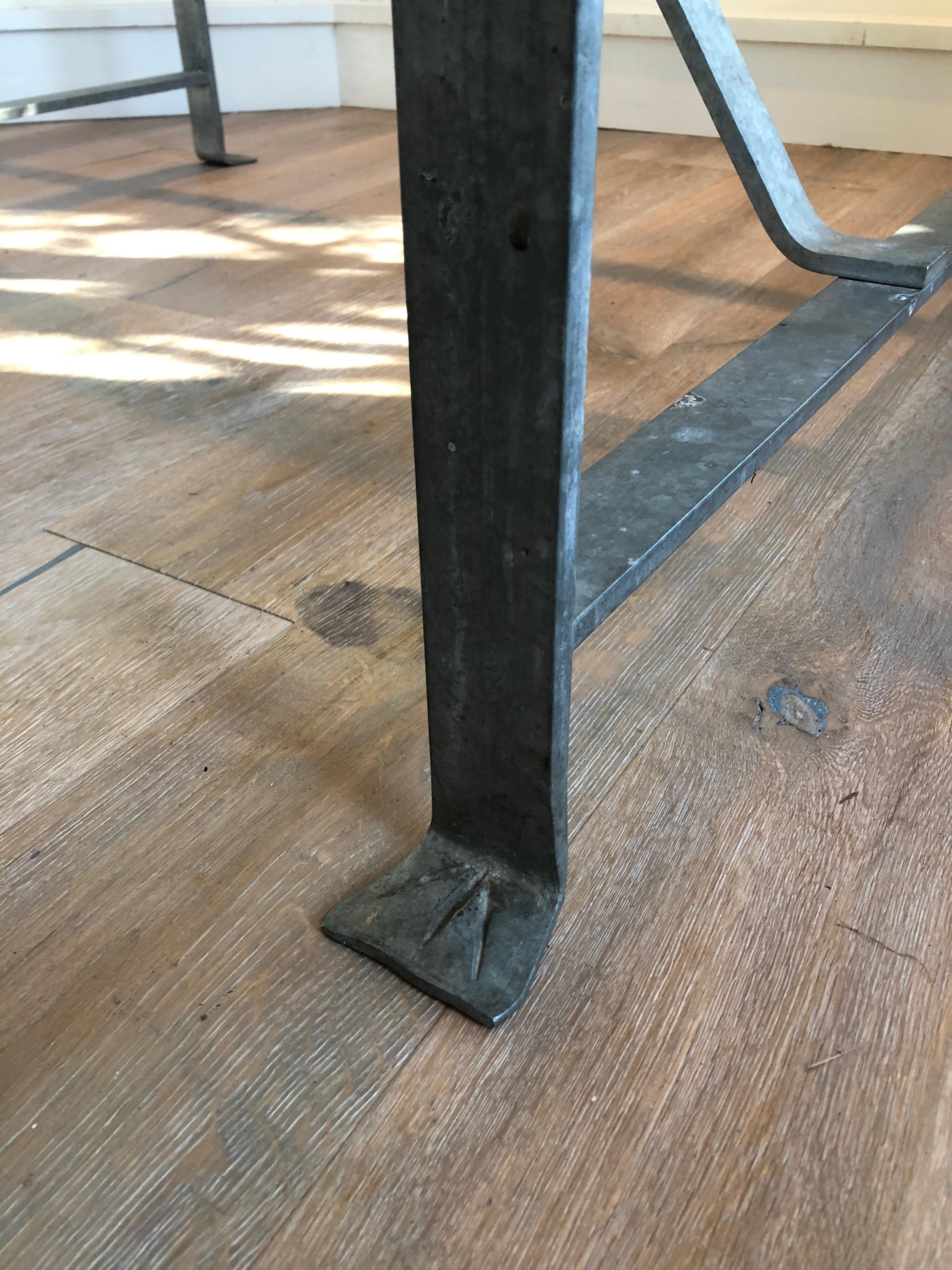 A handsome and substantial steel trestle base dining table with Carrera marble top. Steel base has unique details including 