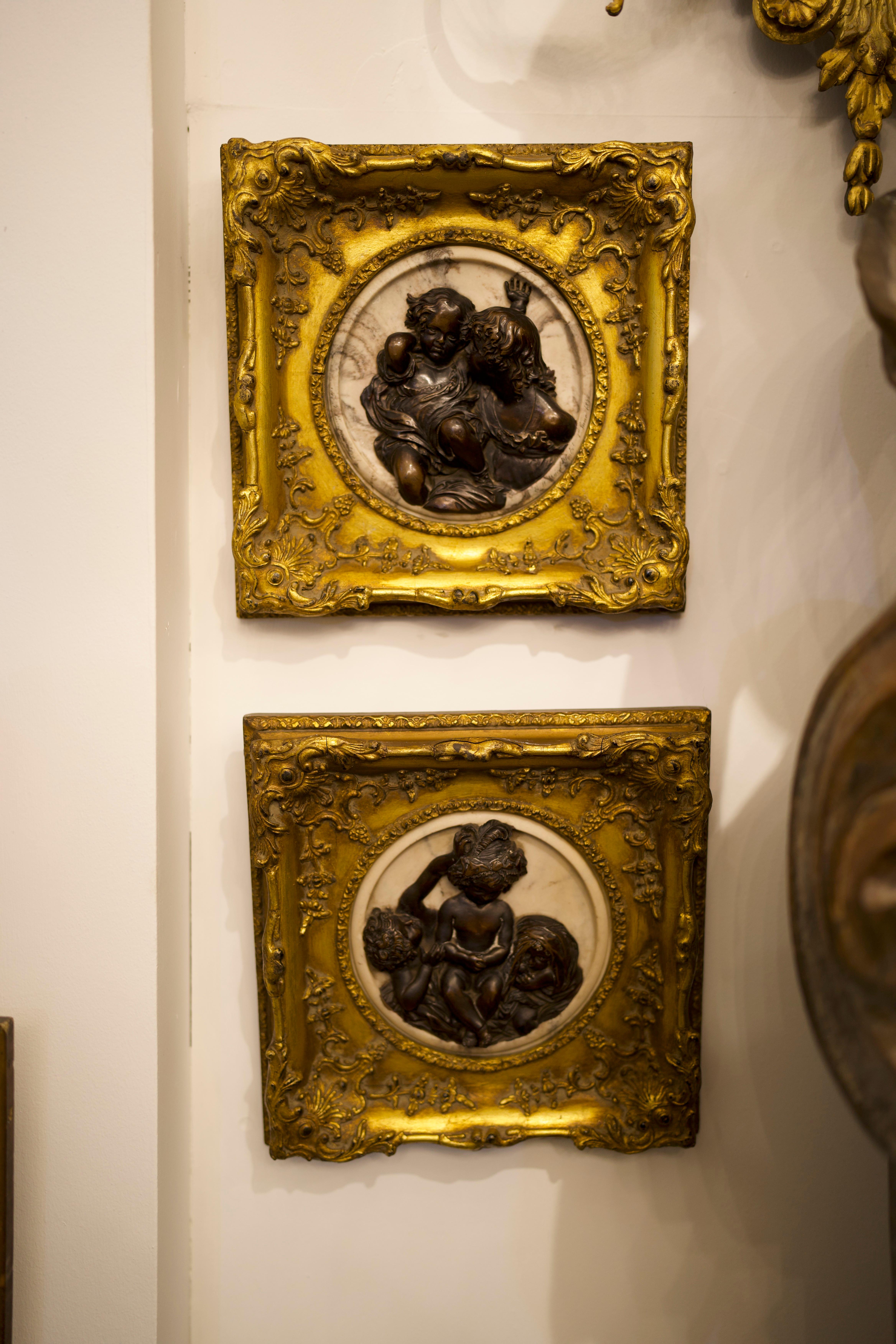 A pair of stunning French early 20th century marble, bronze and giltwood cameo wall art. Housed within an exuberantly carved gold gilt frame of square form, the conformingly shaped white Carrara marble plaque is mounted with the right profile view