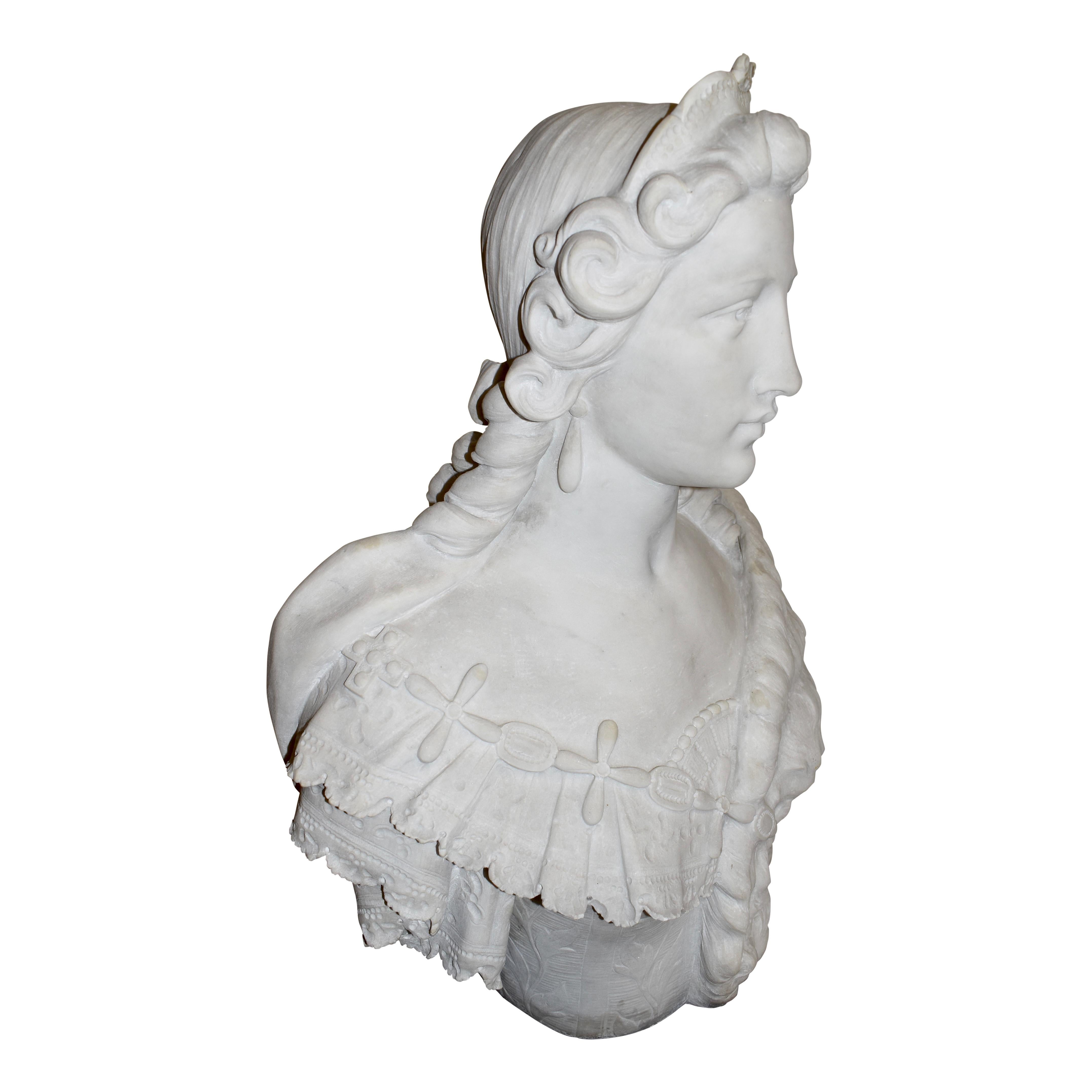 As an early rendition of Marie Antoinette, Queen of France, this marble bust depicts her in her youth wearing a simple hairstyle with ringlets tied back in a bow and a small tiara crowning her head. A fur drapes elegantly over her left shoulder,