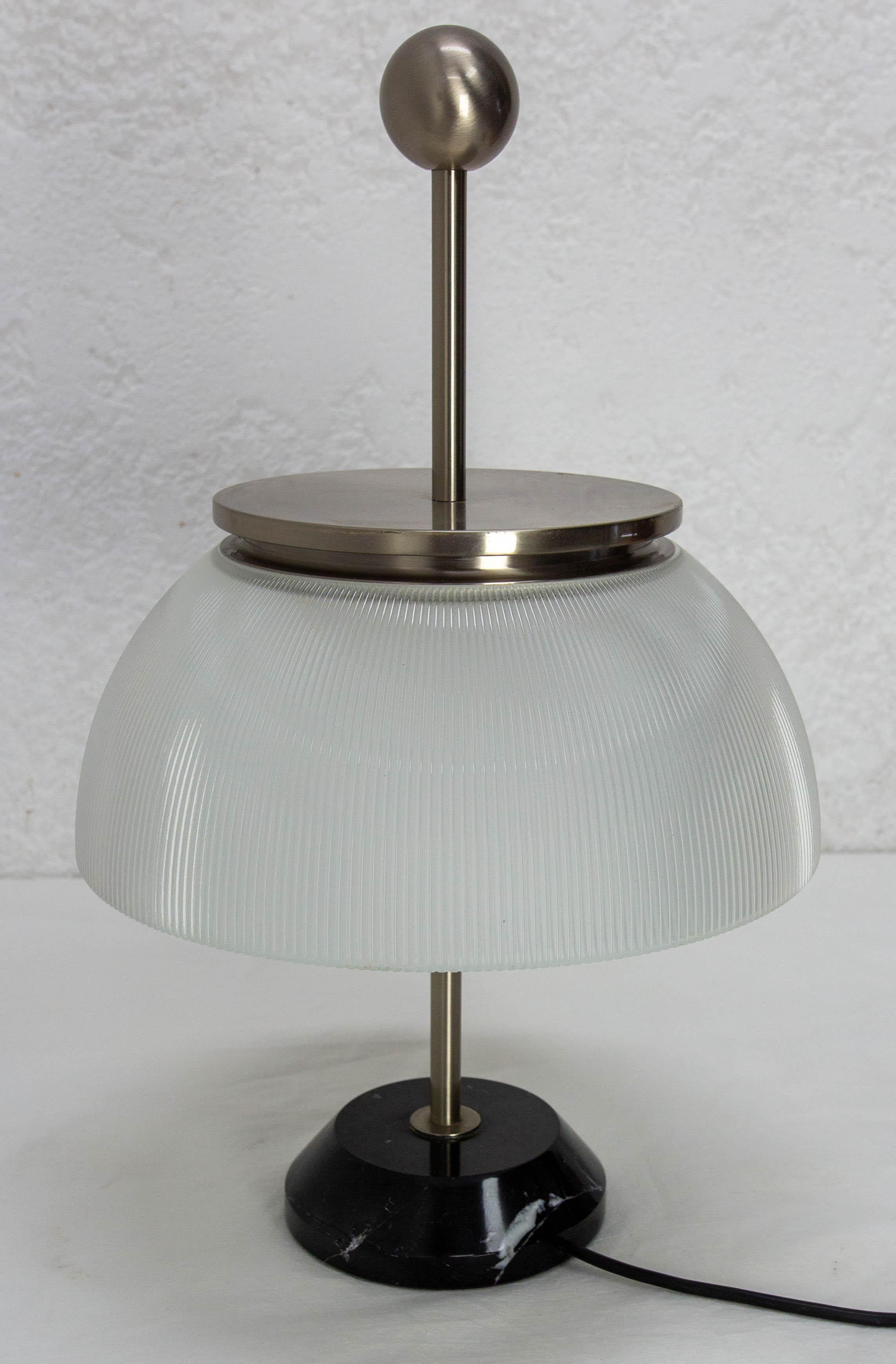 La lampada da tavolo Alfa di Artemide è un classico degli anni '50, disegnata nel 1959 dal famoso Sergio Mazza. La sua caratteristica struttura in metallo nichelato sostiene un prezioso diffusore in vetro di cristallo. Le parti in metallo tornite a