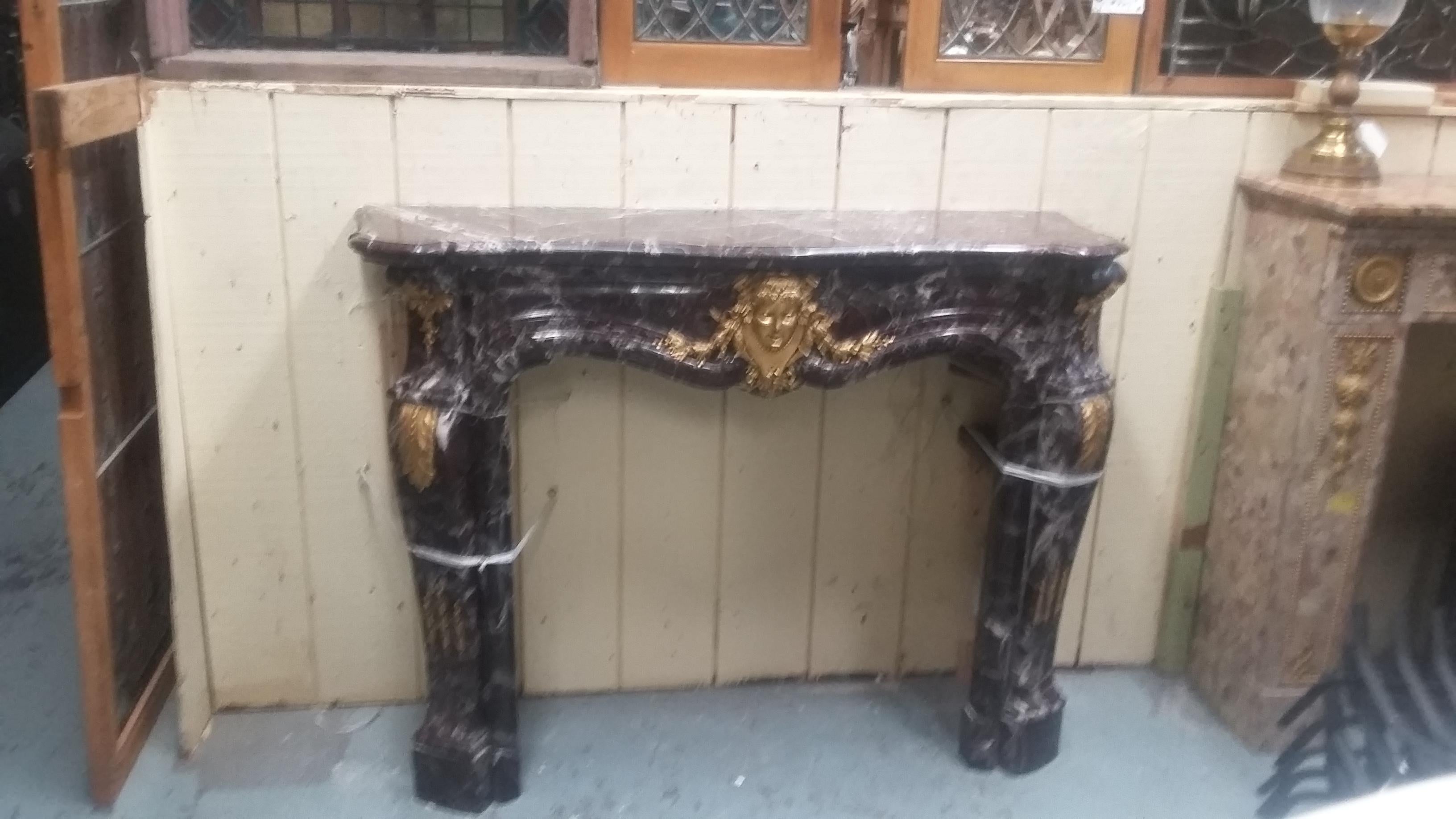 Beautiful vintage French marble mantle. A great late 19th century or possibly early 20th century example of fine craftsmanship. Great rouge color with bronze ormolu details including Victorian woman's face in the center. (2 repairs made to the right