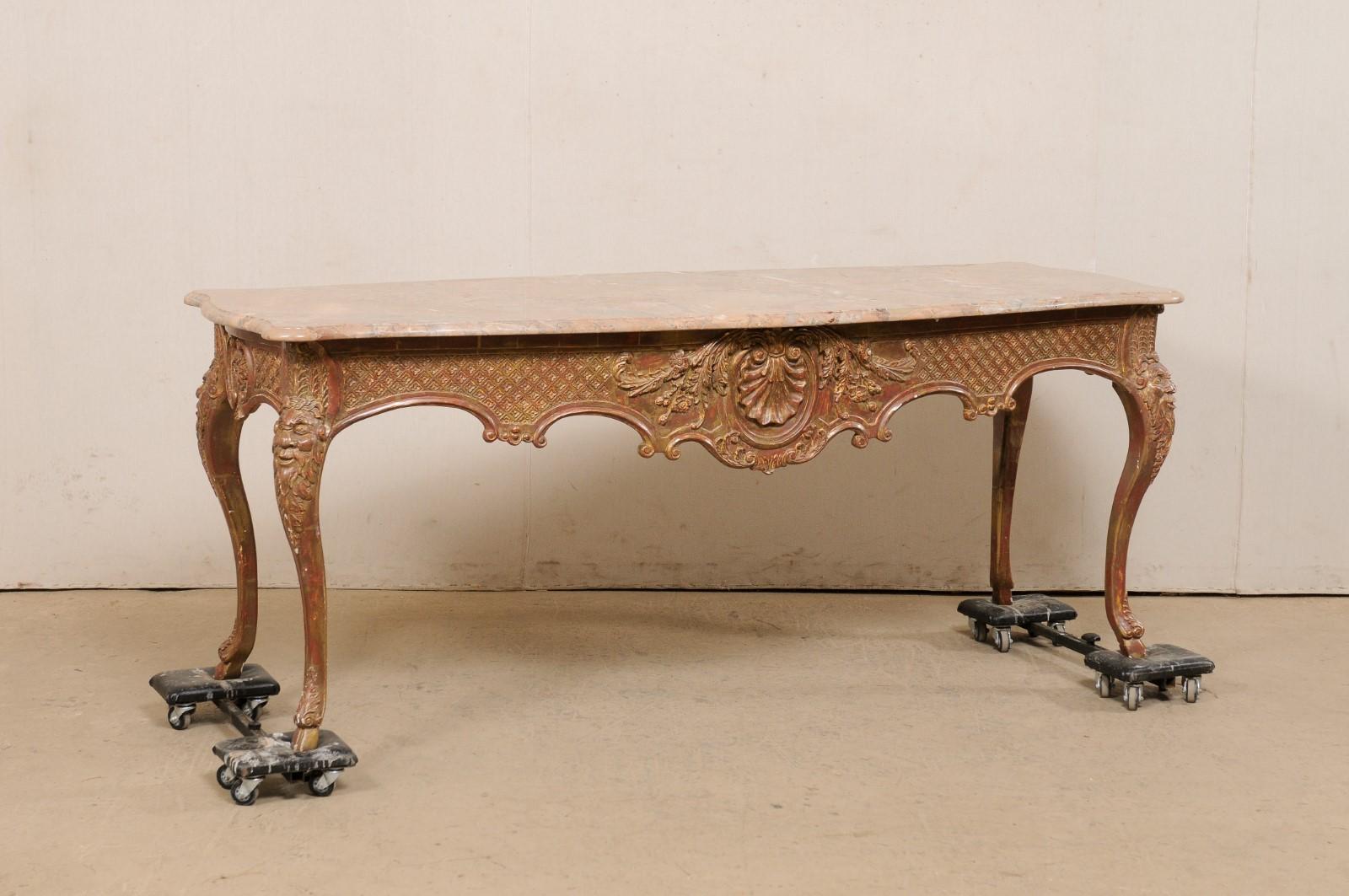 A French ornately carved-wood center table with shapely marble top. This vintage table from France is nicely sized at approximately 6.75 feet in length. The mostly rectangular shaped marble top is gracefully bowed along either long end, has rounded