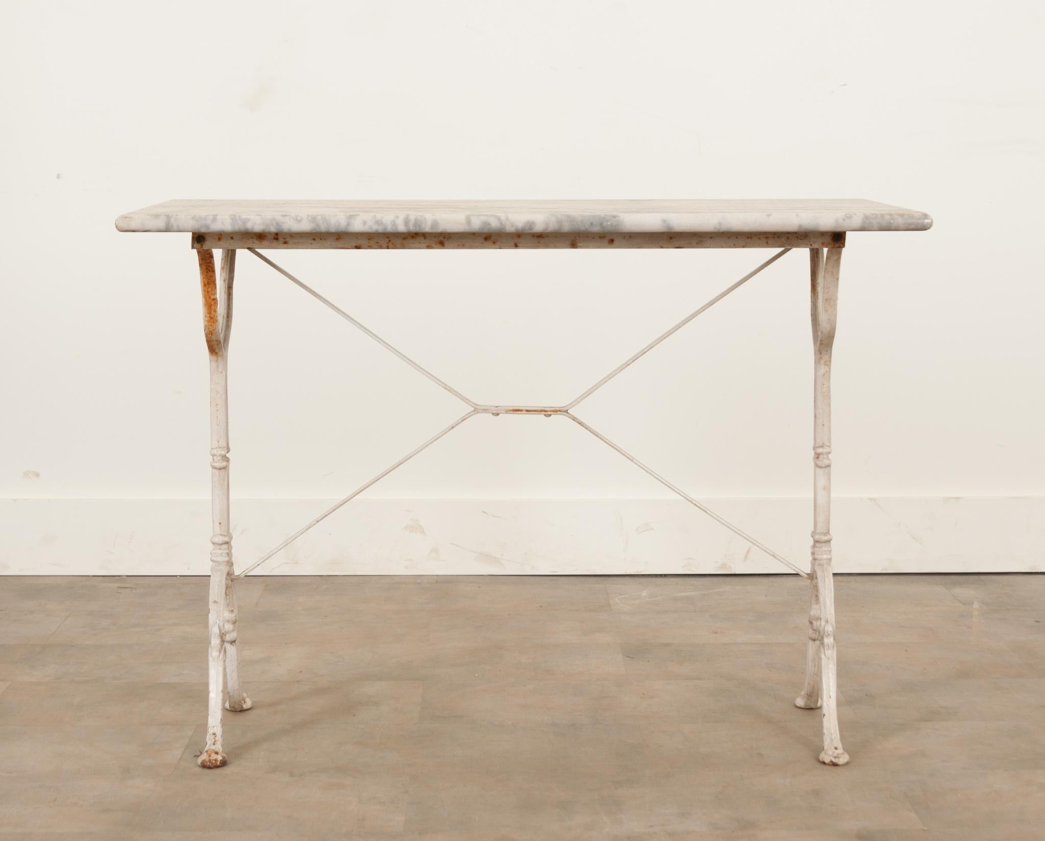 A lovely French marble-top bistro table with a classically styled white painted iron base The white marble top has beautiful inclusions throughout and the base has X-form supports and the scroll-form feet.
