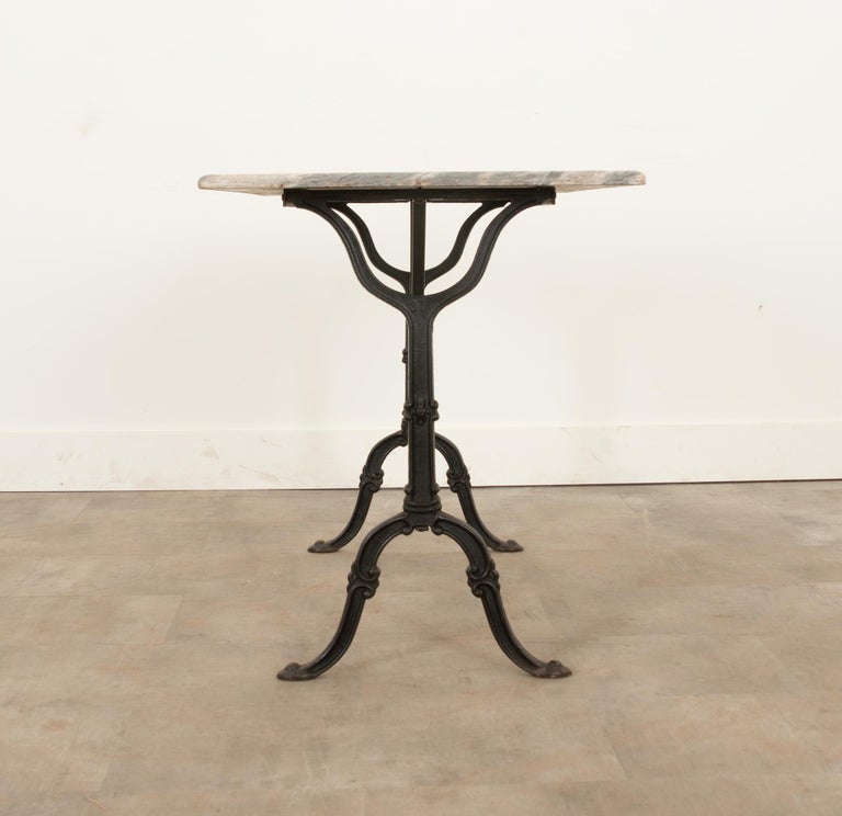 A delightful French marble-top bistro table with a classically styled black painted iron base. The marble top has beautiful charcoal veining and inclusions throughout. The base has X-form supports and the scroll-form feet.