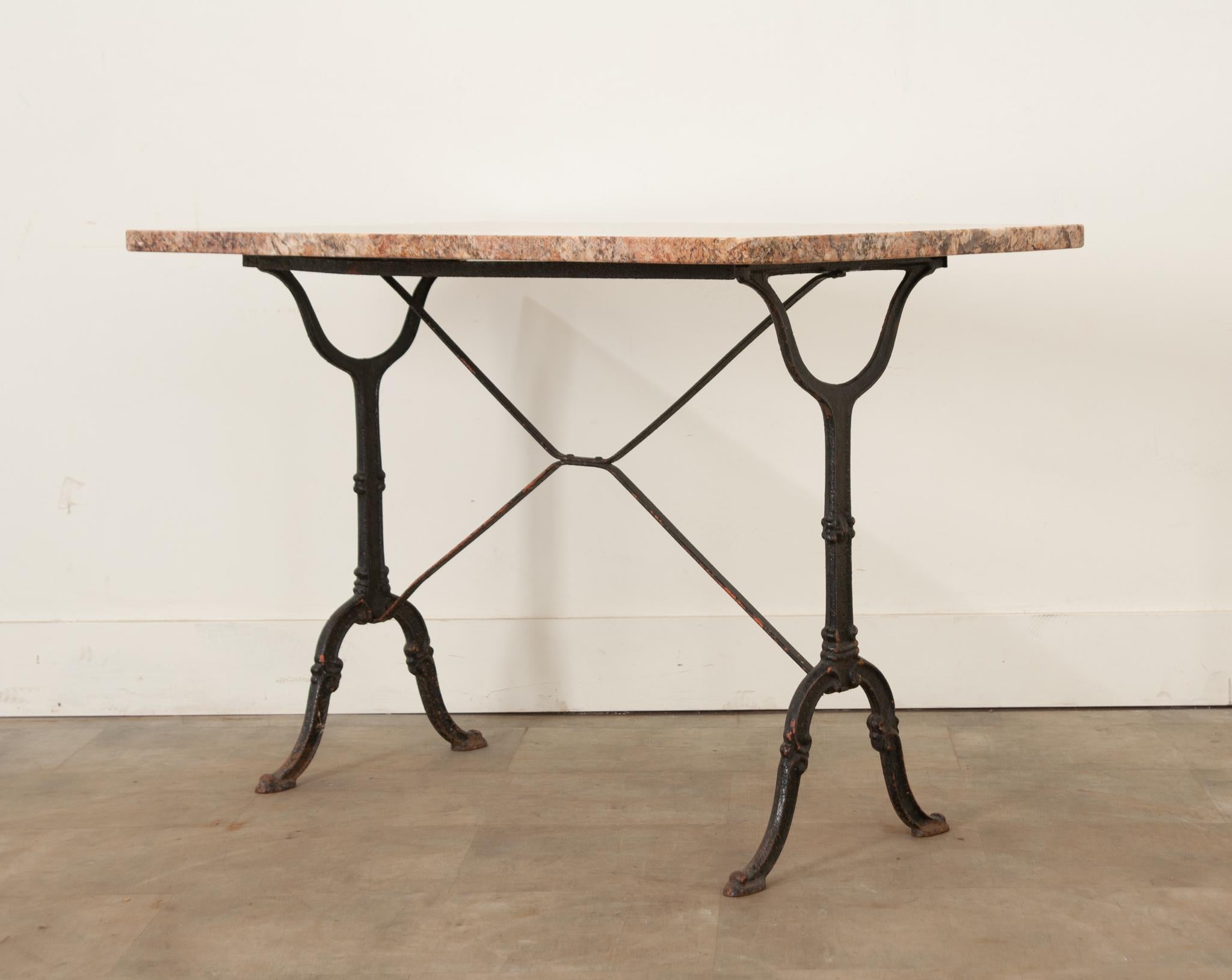 A lovely French marble-top bistro table with a classically styled black painted iron base. The more recent stone top has beautiful red, brown, and cream patterns throughout. The base has X-form supports and pad foot styled feet. Be sure to view the
