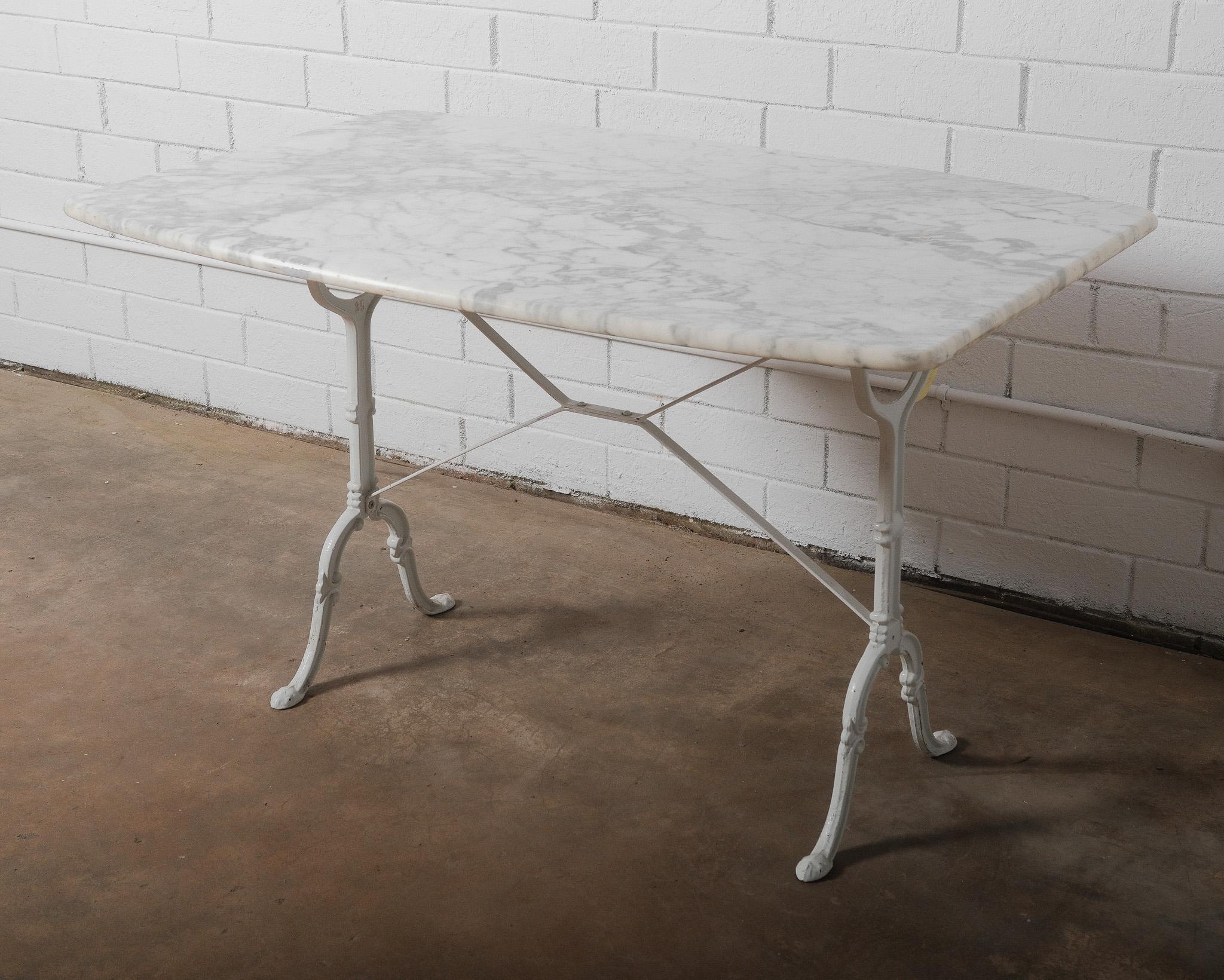 Questo elegante tavolo da bistrot francese presenta un piano in marmo bianco di Carrara splendidamente venato e dai bordi morbidamente arrotondati. La base in ghisa, dipinta di bianco, ha una silhouette aggraziata con dettagli intricati sulle gambe