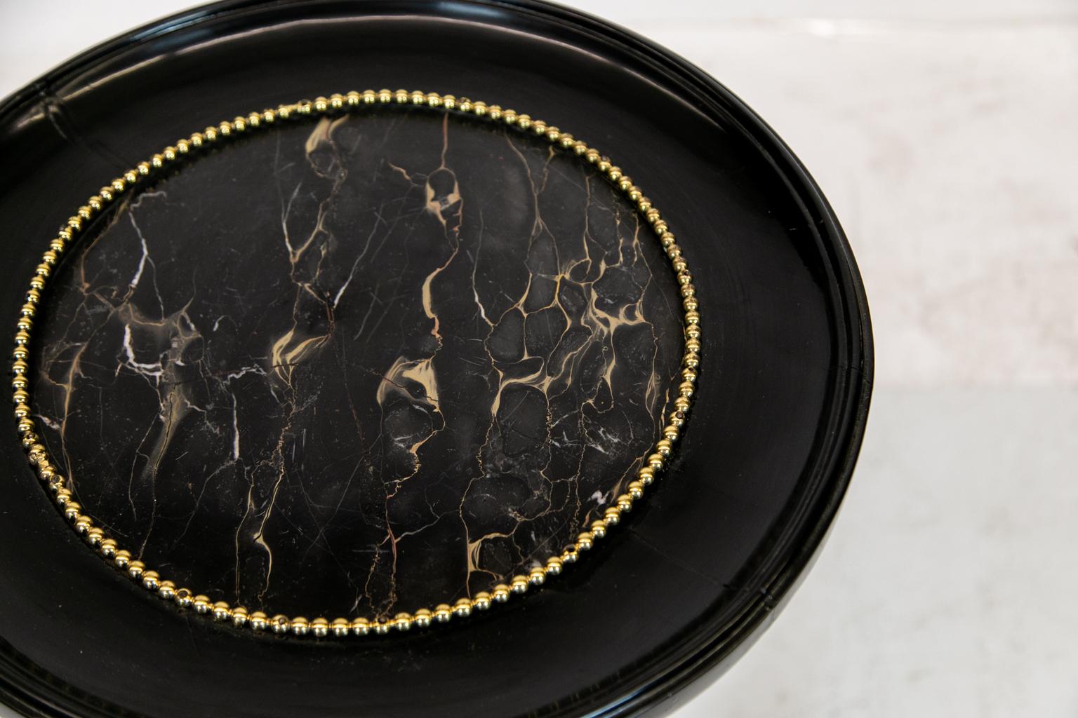 French marble-top black lacquered tripod table with heavy brass ornamentation. This piece has cast brass ball and claw feet. The balls are made of black lacquered wood.