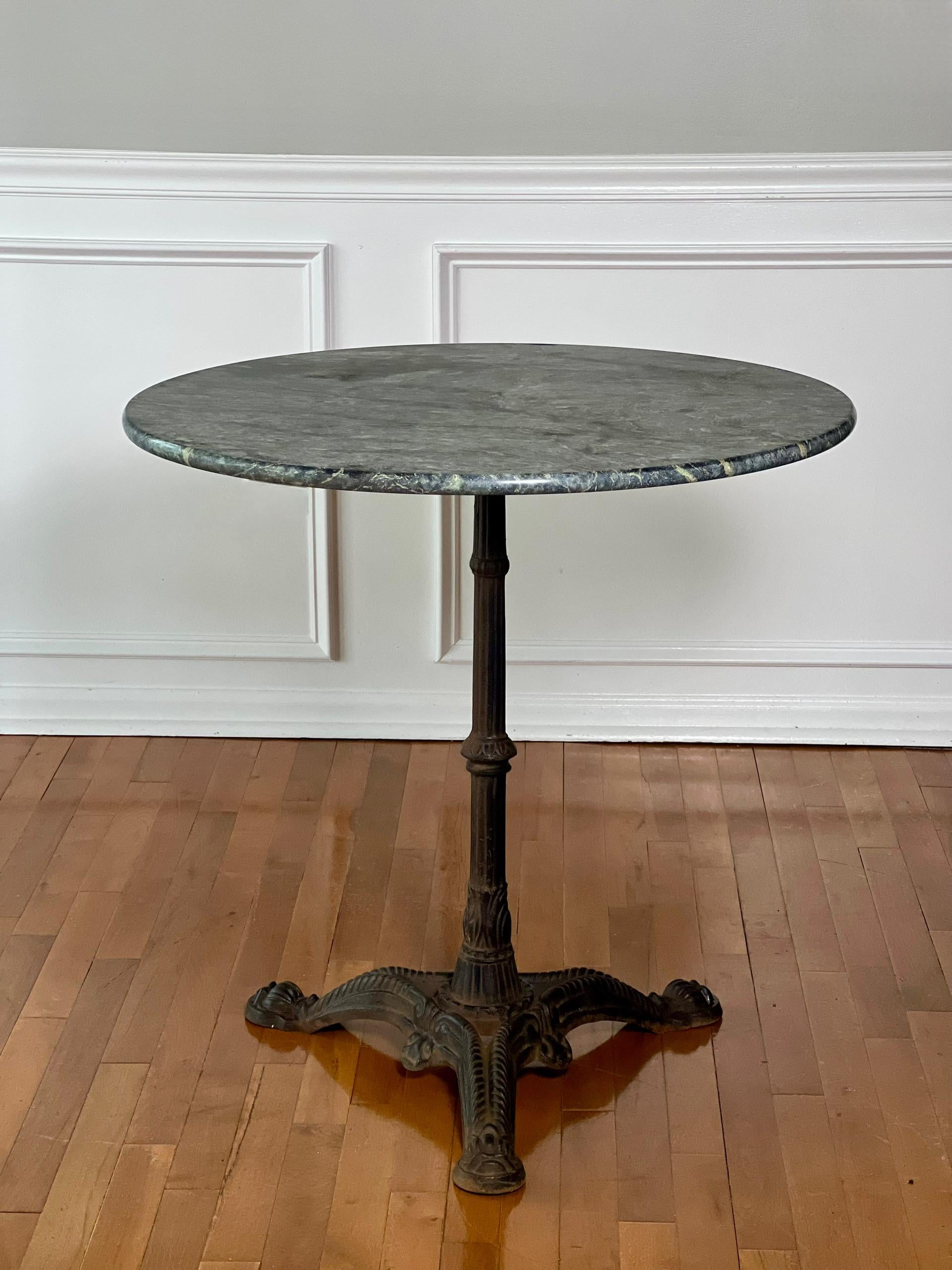 Klassischer französischer runder Bistro- oder Cafétisch aus Gusseisen mit Marmorplatte, Anfang des 20. Jahrhunderts. Schicker Tisch mit begehrenswerter, gealterter Patina in gutem Zustand und mit viel Charme der alten Welt. Die dunkelgraue