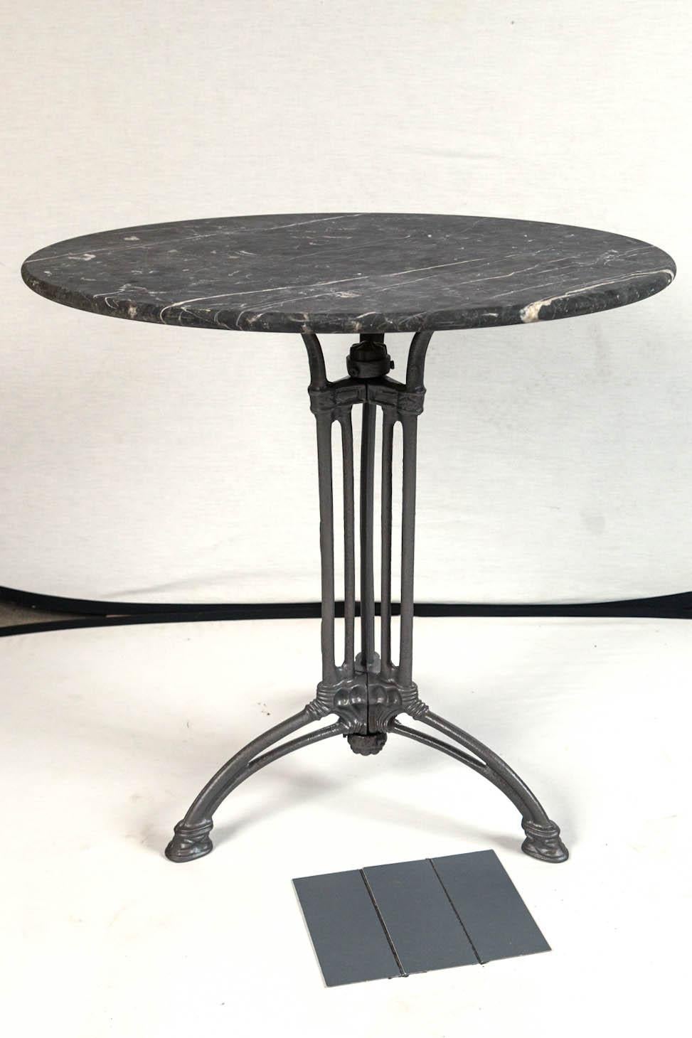 French marble top cast iron Bistro table, circa 1900. Original gray marble top with white veining. The tripod iron base has detailed cast designs in the Art Nouveau style.