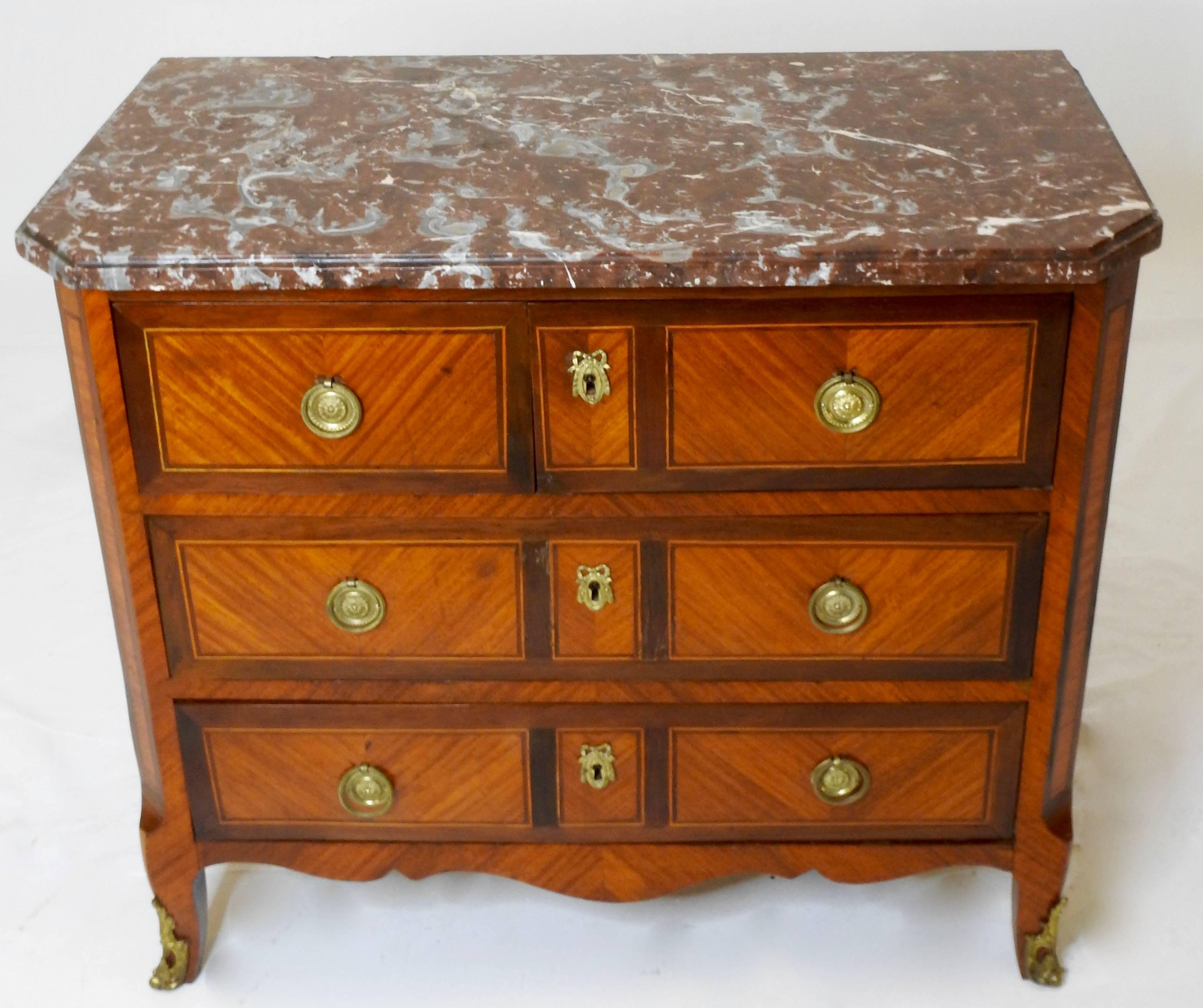 Cabriole legs grace this marble top chest with ormolu detailing. The top section is two drawers and the bottom two sections are singles. The wood inlay details are elegant and geometrical. Ormolu details the front two legs. The pulls are a simple
