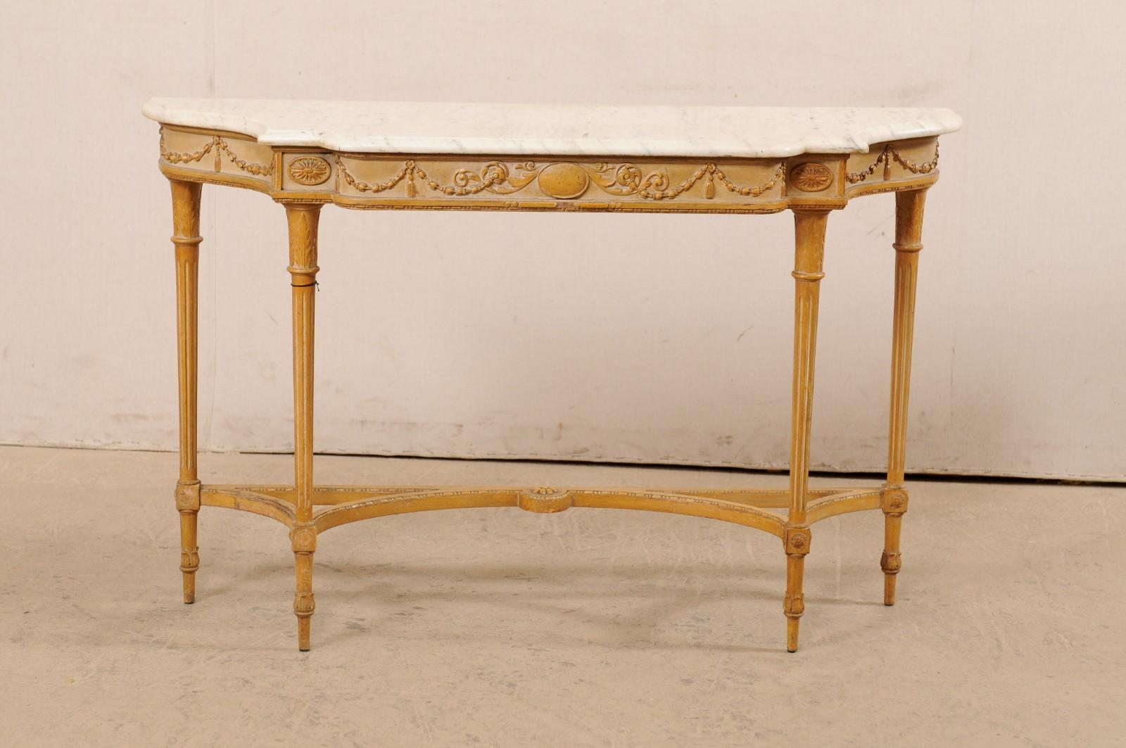 A French carved-wood console table with marble top from the mid 20th century. This vintage table from France has been designed with Neoclassical influences, and features a marble top which rests upon an apron carved with stringing garlands and an