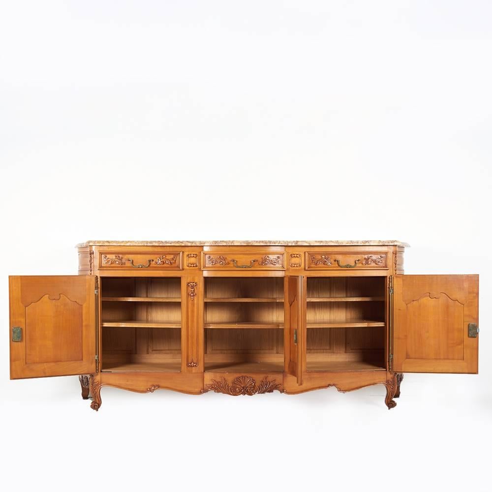 A lovely-quality French Louis XV style buffet or sideboard, the sides featuring solid cherry curved panelled sides, the doors also of solid panelled construction and embellished with hand-carved details.
Above the three doors are three drawers,