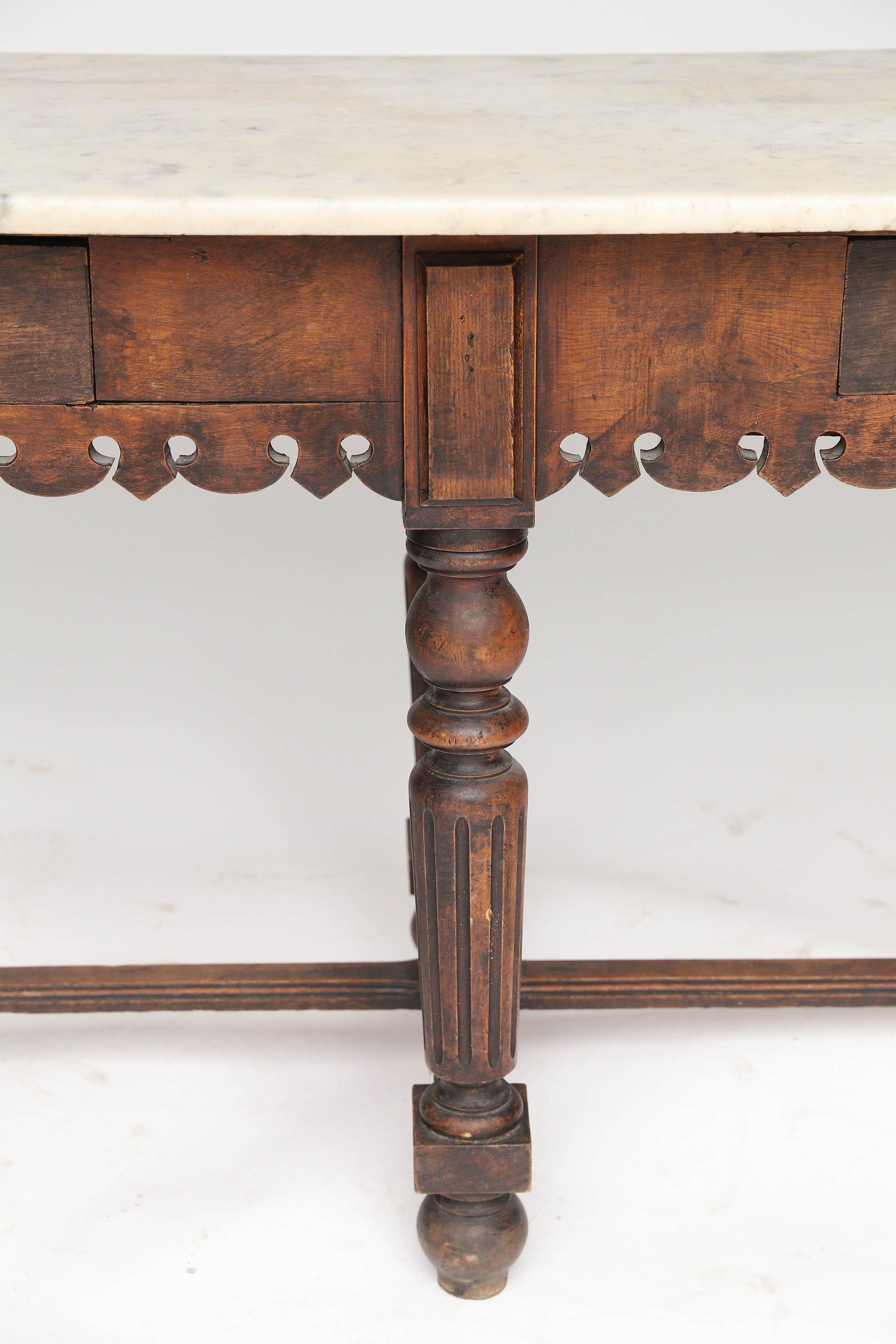 A spectacular antique French marble-top oak butcher table. Featuring an oak base with scalloped apron on both sides and two drawers for storage would make this piece a great addition to any kitchen. The beautiful aged patina marble top gives the