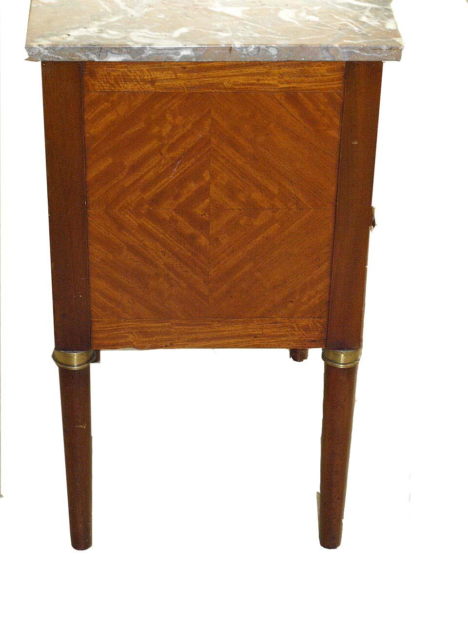 French marble top one drawer stand, the drawer and door are inlaid with ebony and boxwood, and also cross banded around the edges, sides with matching veneer pattern, the round and tapered legs with brass caps at the top.