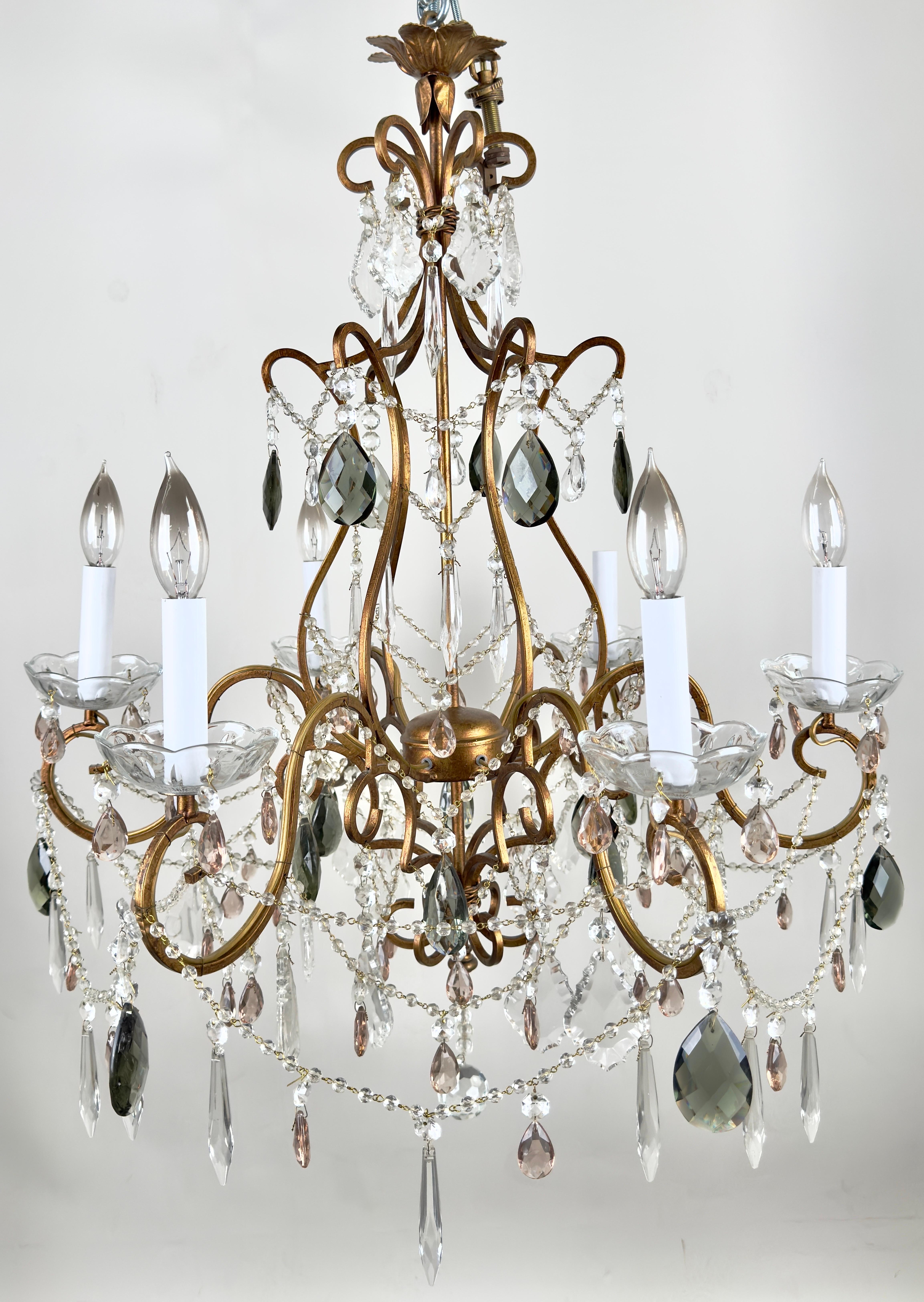 A French Marie Therese Hollywood Regency style chandelier, featuring an exquisite French design and dazzling cut crystals and  six elegantly curved arms. Each arm of the chandelier is adorned with intricate scrolls,  French style pendaloques, and