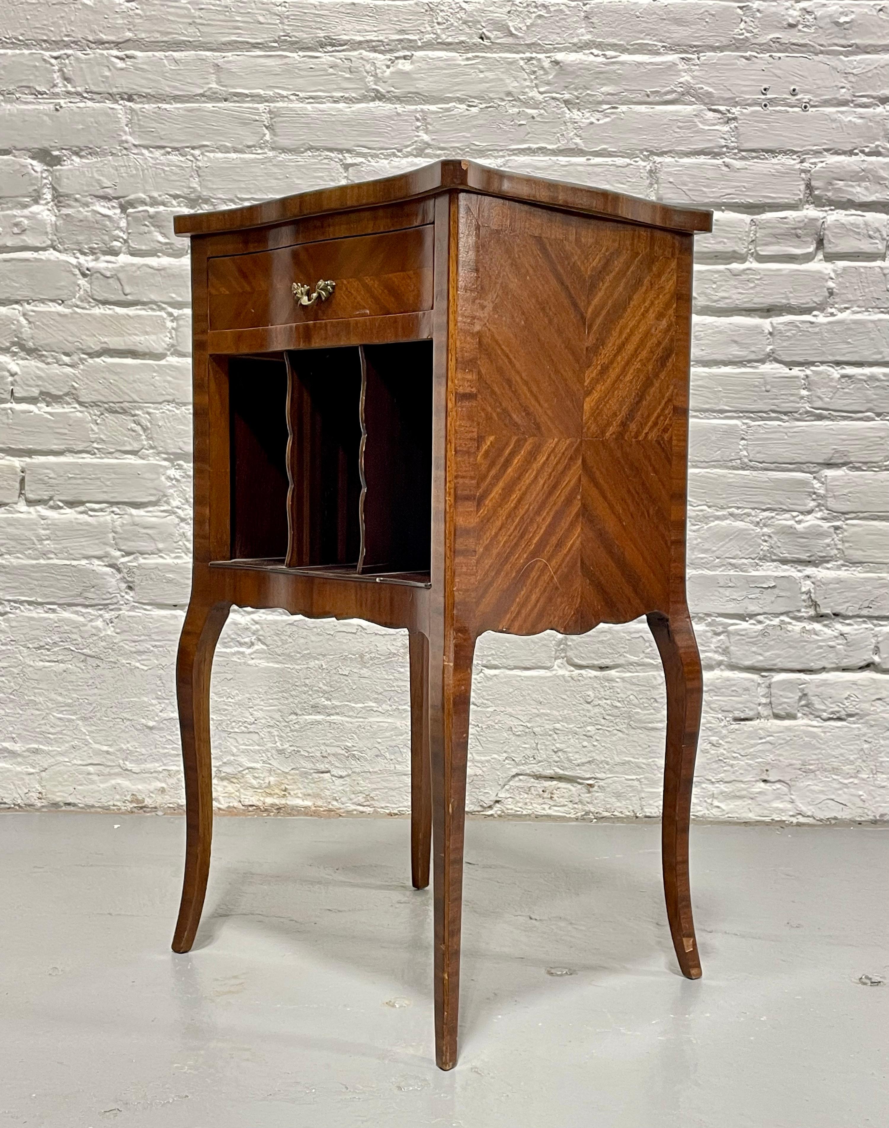 A fantastic little French Marquetry Bedside Table with gorgeous bookmatched wood detailing along each side and across the tabletop. The layout offers a dovetailed drawer and three partitioned spaces below, perfect for displaying books and magazines