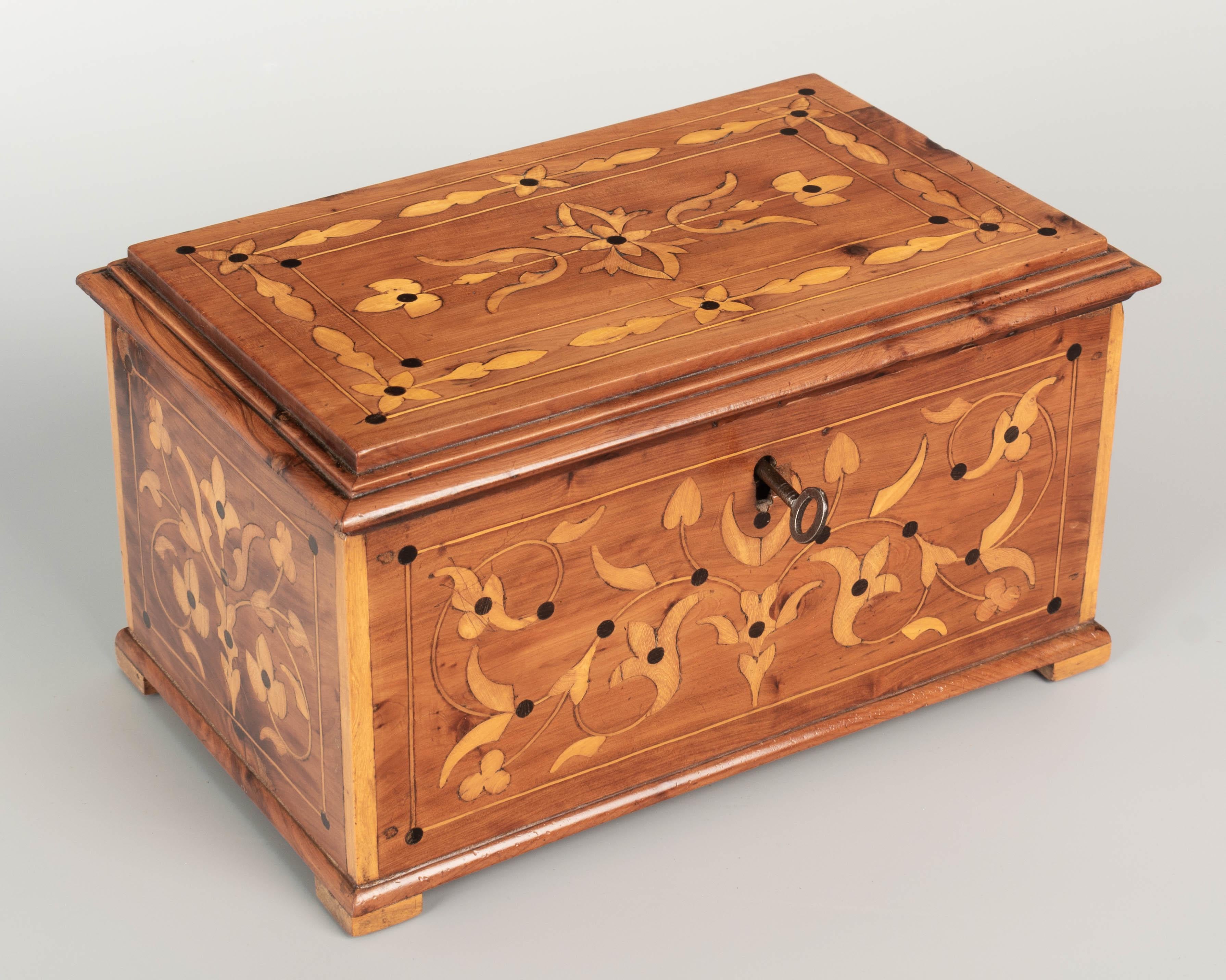 An early 20th Century French marquetry box made of solid cherry with decorative inlay of yew wood. Interior has a lift out tray with divided compartments. Working lock and key. Circa 1900. 
Dimensions: 11.25