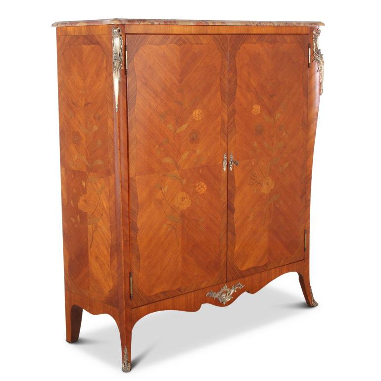 A French, Louis XV-style two-door cabinet, or armoire, in kingwood; with lovely floral marquetry inlay, the doors opening to reveal three adjustable shelves. The case is accented with Fine gilt bronze mounts and is capped with the original shaped,