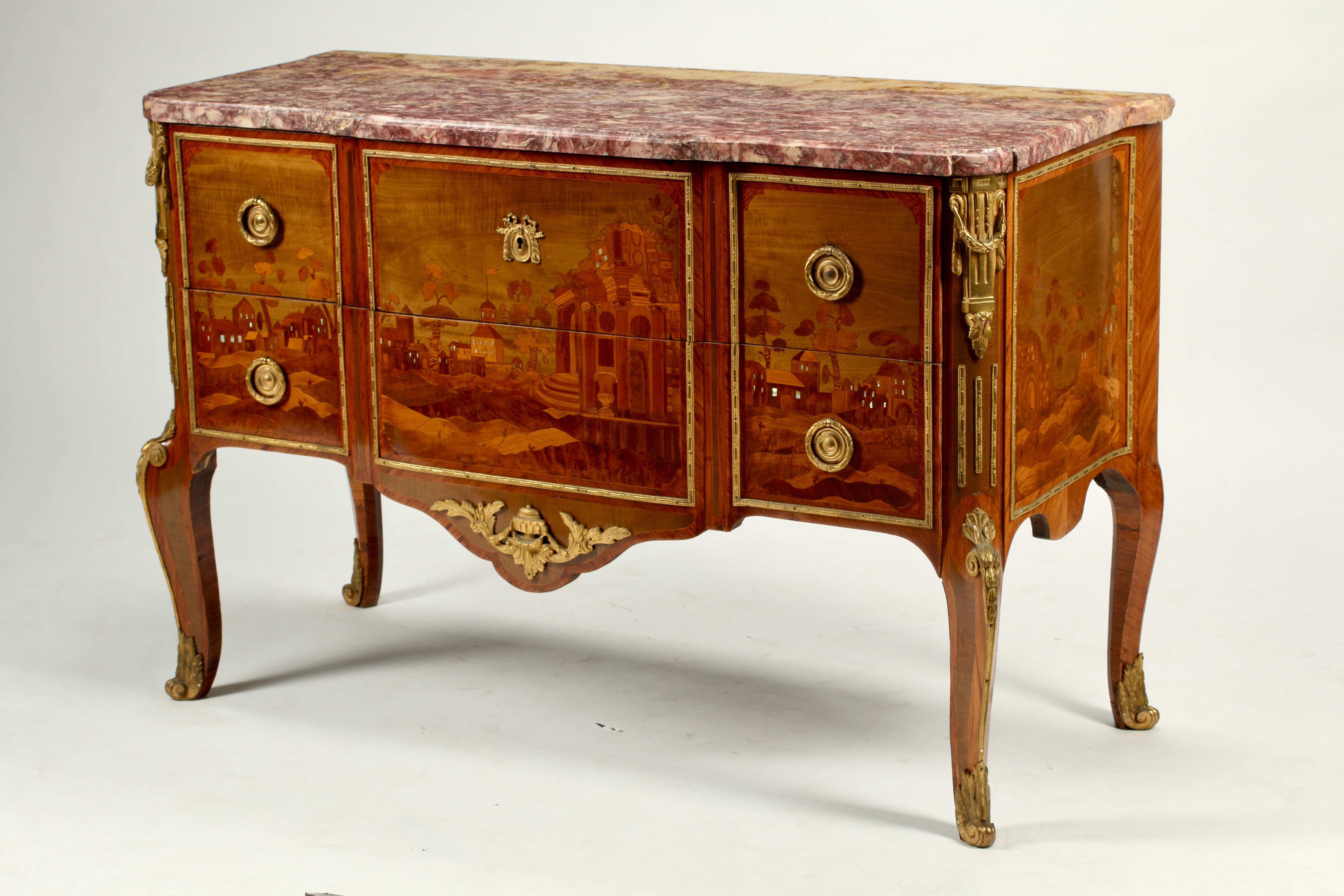 An exquisite French Louis XV-XVI transitional style commode with dore bronze ormolu mounts and original marble top. 
The fine marquetry depicting a townscape was crafted from the most beautiful exotic fruitwood and mother of pearl inlay in the