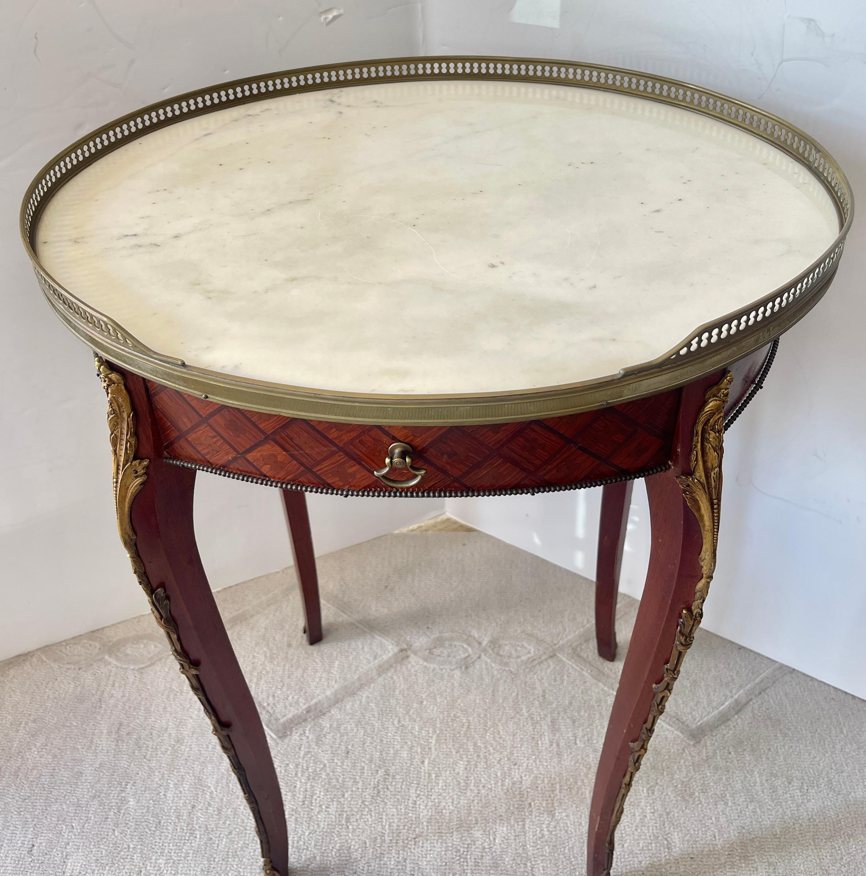 Just in, this charming French Wood Marquetry gueridon side table with a Brass Gallery and original White Marble Top, Early 20Th. Century.
This table has elegant cabriole legs that are adorned with Bronze mounts.
This table is of oval shape, the