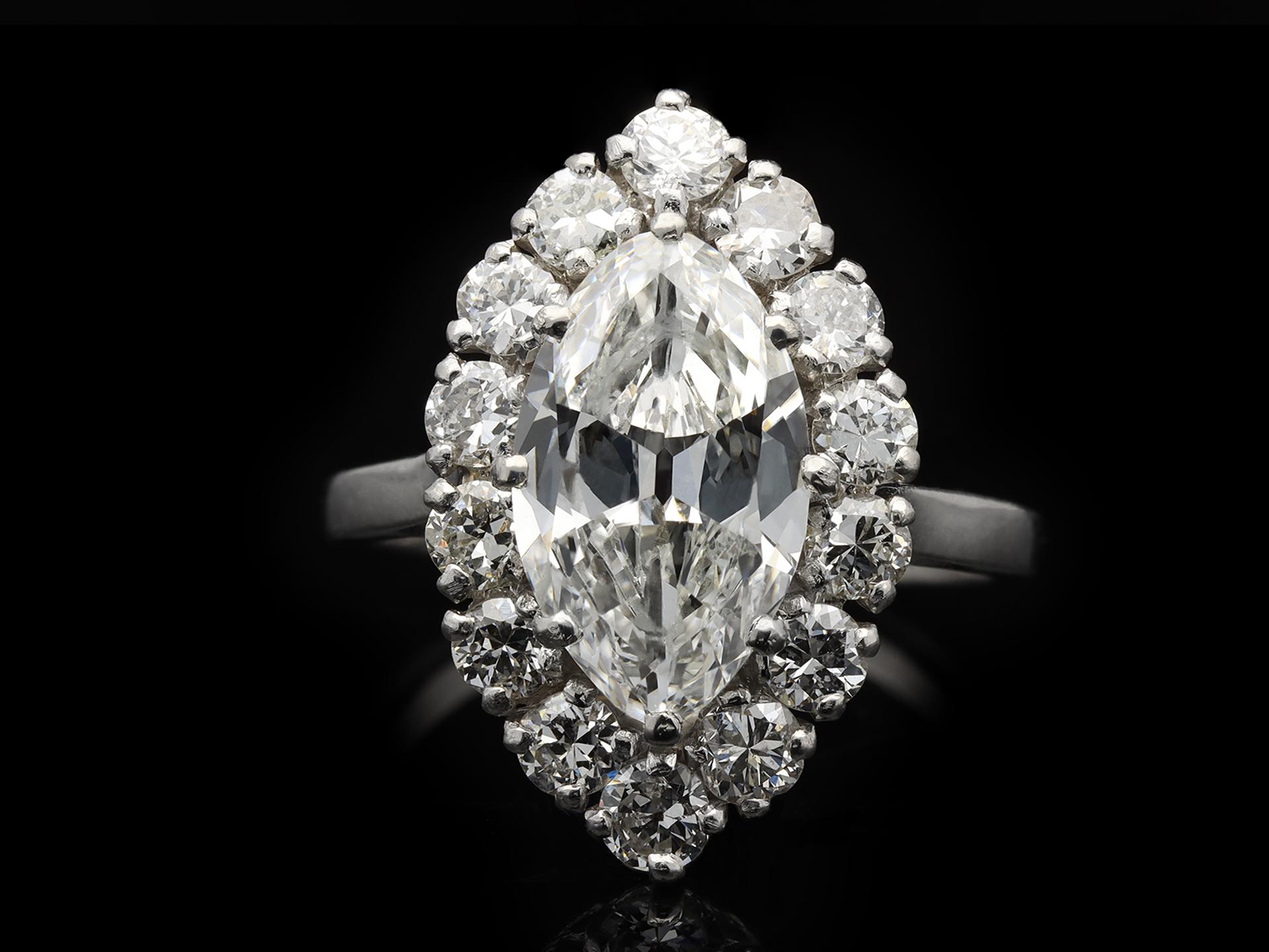 Vintage marquise diamond cluster ring. Set to centre with a marquise shape old cut diamond, F colour, VS2 clarity, with a weight of 2.39 carats in an open back claw setting, encircled by a single row of fourteen round old cut diamonds in open back