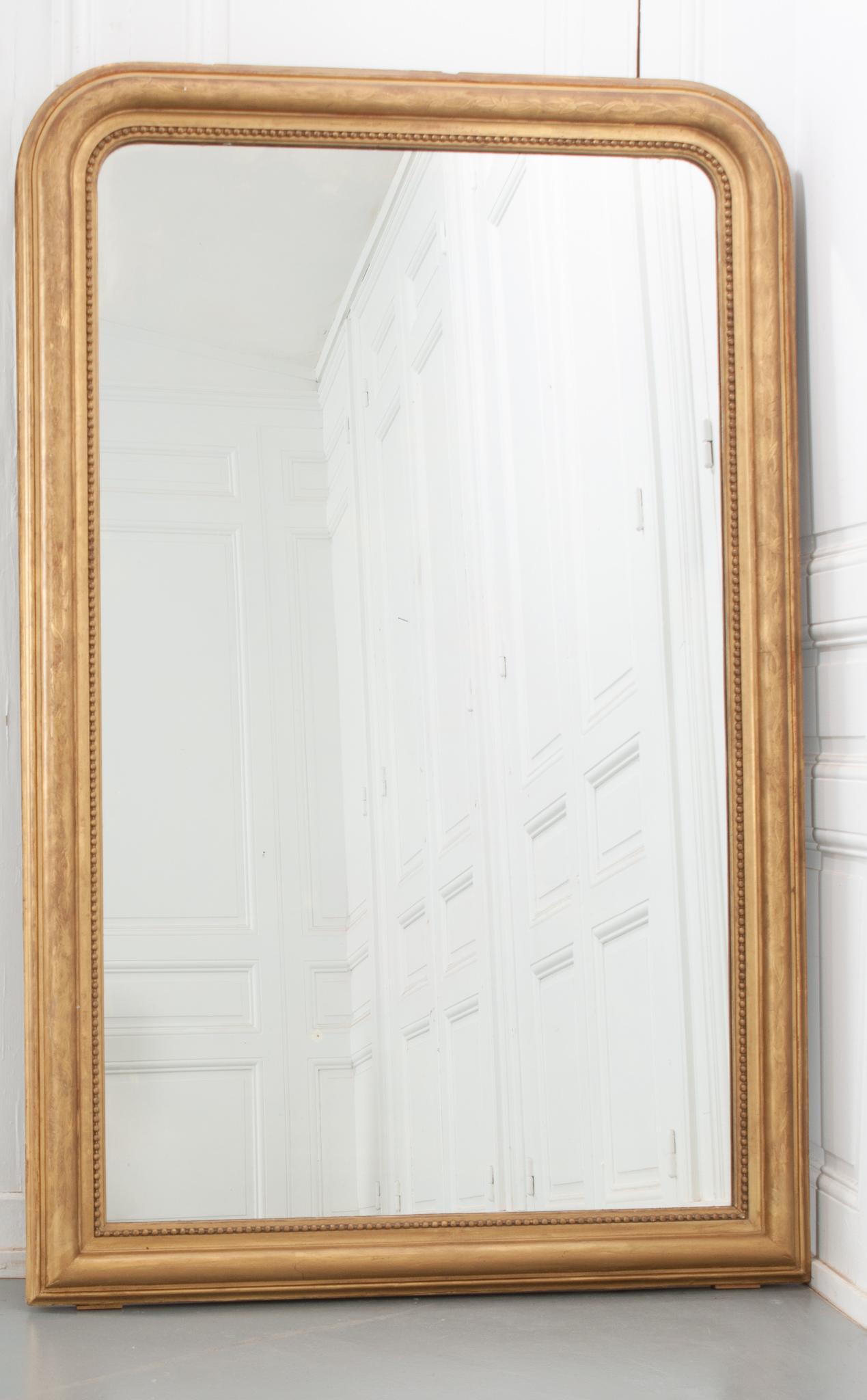 This fantastic gold gilt Louis Philippe-style mirror still features its original mirror plate, circa 1890. The frame has a finely detailed motif of flowers continuing around the whole and carved beading bordering the mirror. Bold French red can be