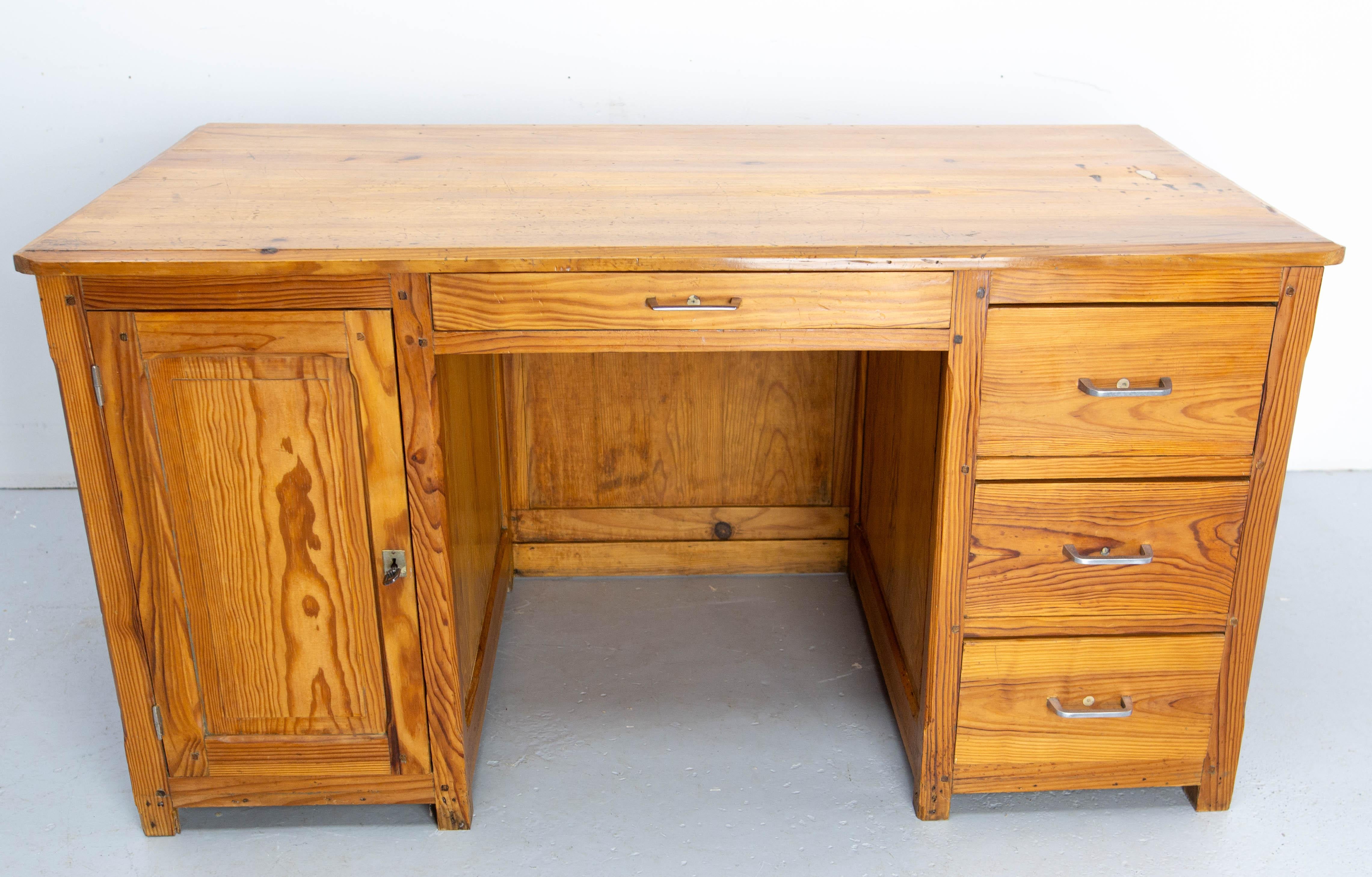 French massive pine desk made circa 1950. 
Four drawers and a cabinet with a shelf.
The cabinet can be locked . The locker is fixed upside down, so the key must also be turned upside down.
Like the locker, the handles have been changed in a previous