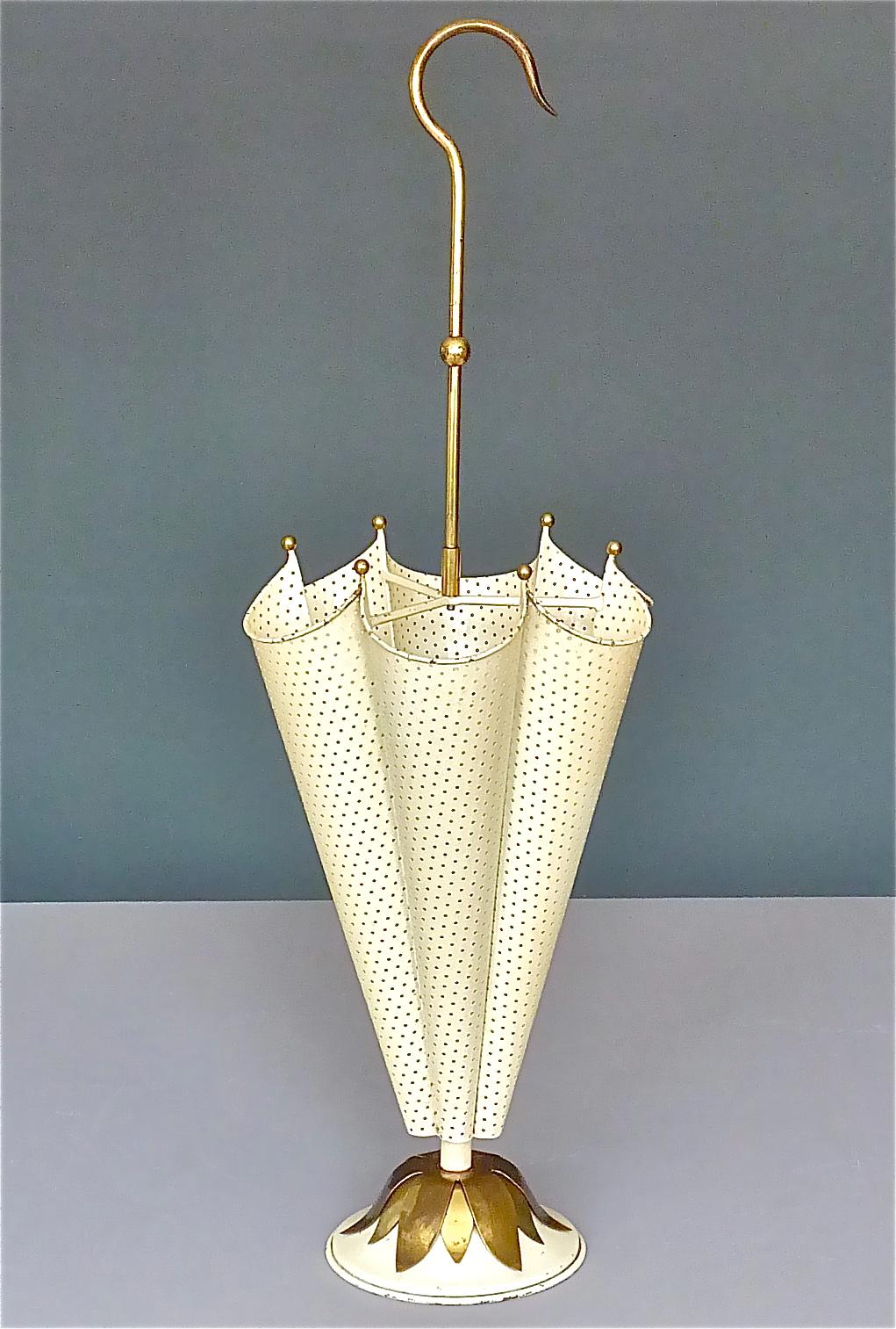 Amazing Midcentury umbrella stand, the design attributed to Mathieu Matégot, France, around 1955. It is made of ivory color to off-white enameled and perforated metal combined with beautiful patinated brass elements and details, designed to an