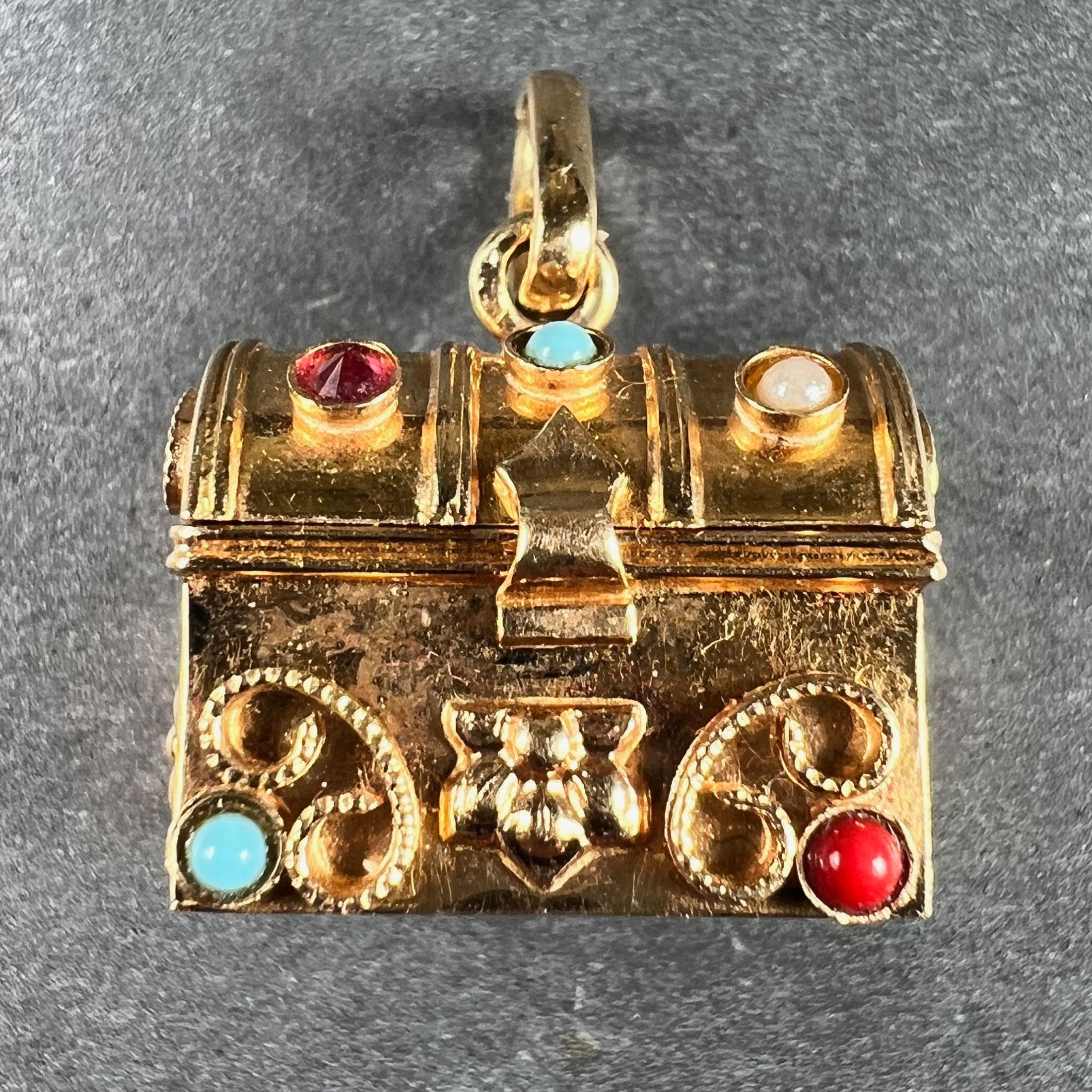 A French 18 karat (18K) yellow gold charm pendant designed as a mechanical gem set treasure chest, opening to reveal a gemstone booty within. The exterior is set with paste and imitation pearls, the interior with paste gems. Stamped with the eagle's