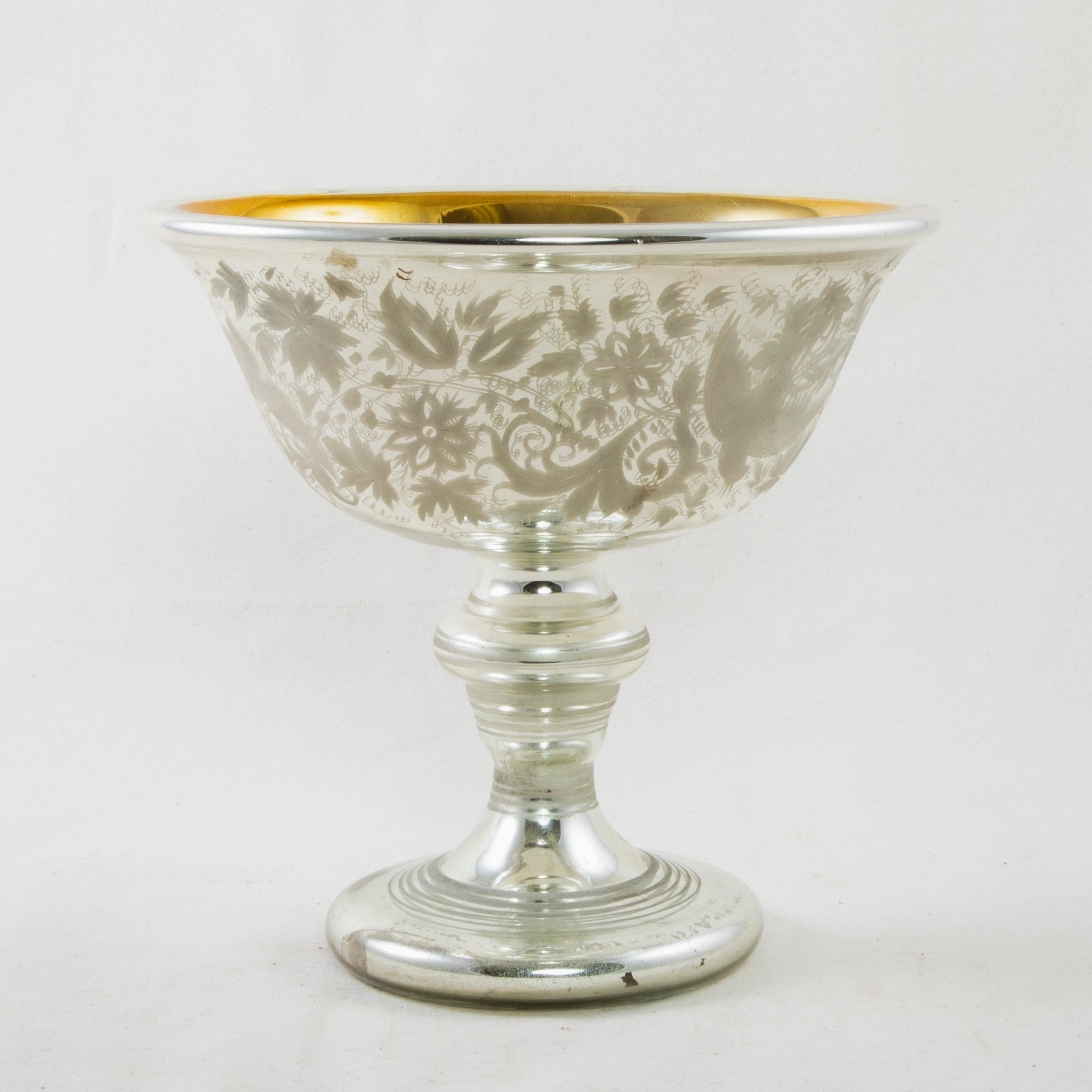 This French mercury glass compote or decorative bowl from the turn of the 20th century features a gold interior and an intricately etched design with flowers and birds around the exterior. The bowl rests on a footed base detailed with etched rings.
