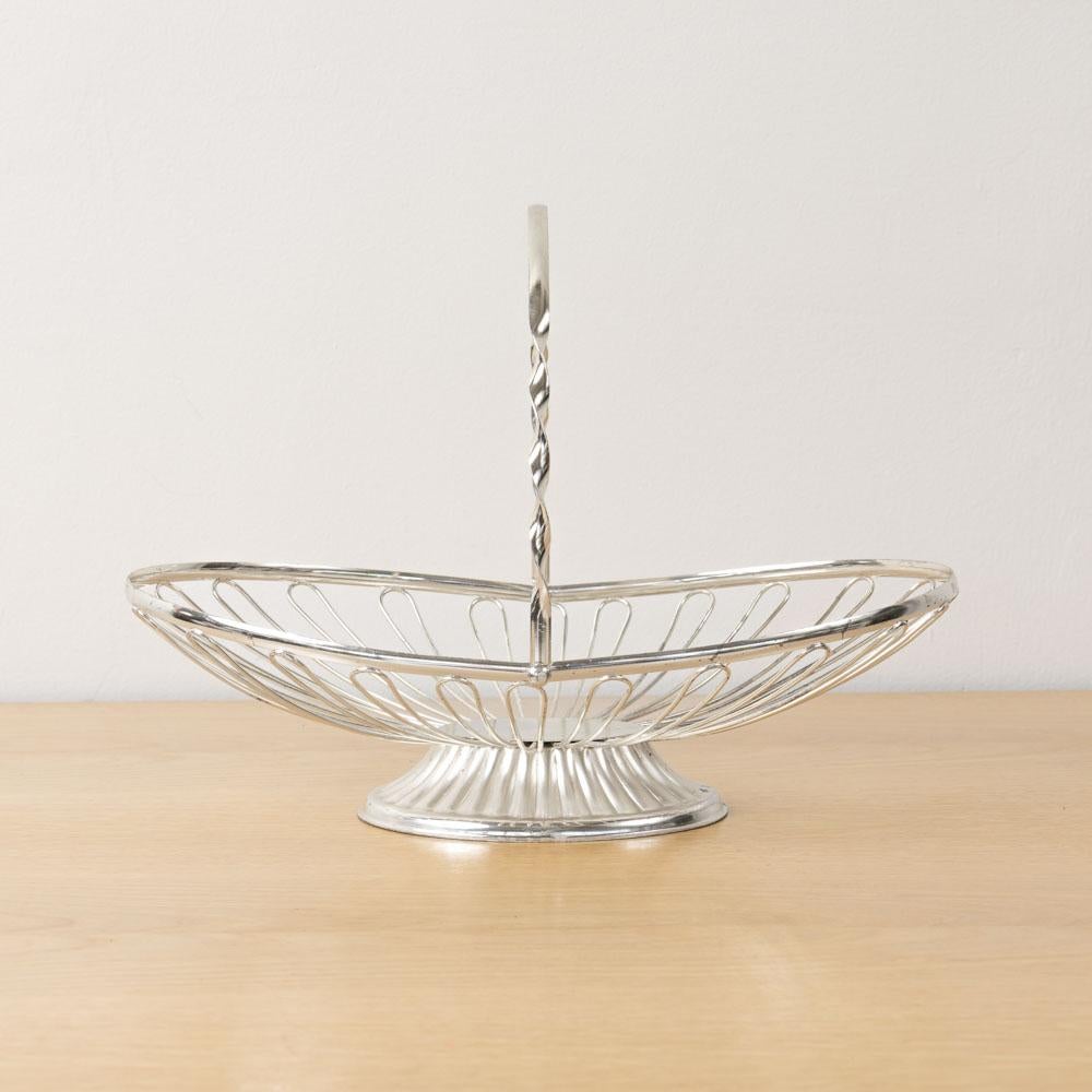 Cestino vintage in metallo unico nel suo genere, con dettaglio di anello aperto e manico in metallo ritorto, proveniente dalla Francia. Di forma ovale, poggia su una base con piedi. Perfetto come oggetto decorativo o come cesto di frutta. L'altezza